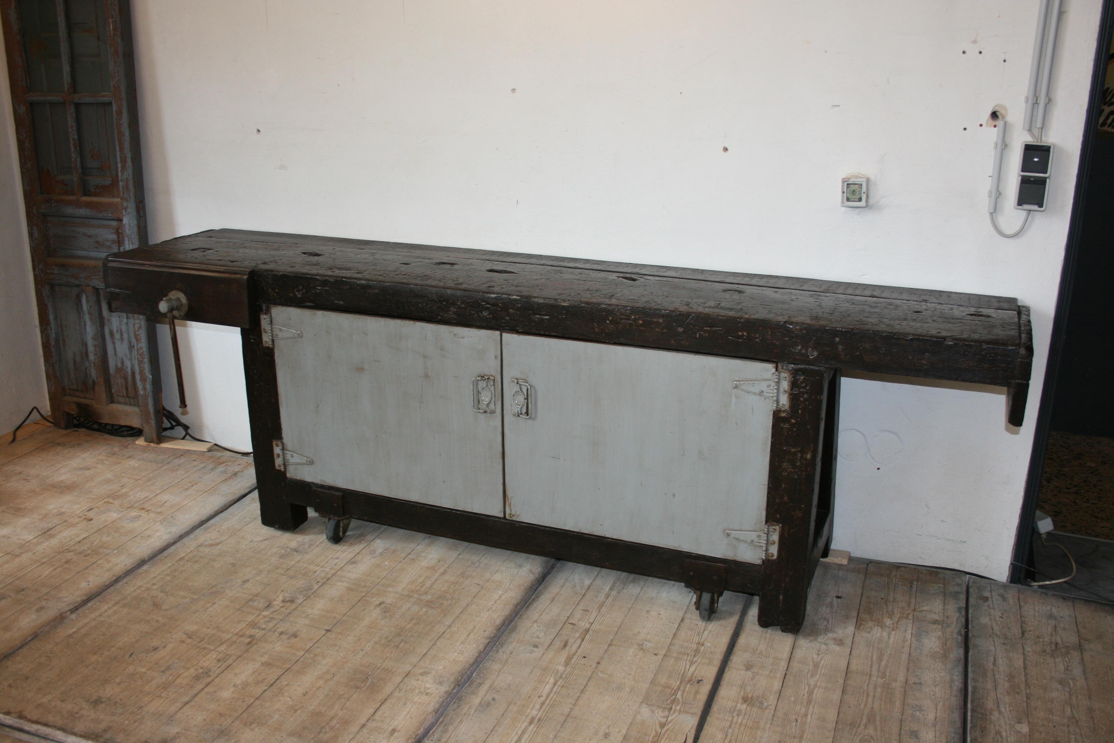 Massive old industrial oak workbench from an old factory in Belgium.
This special workbench is movable on four original old industrial rollers and has below two doors, which have been retrofitted over the decades, behind which are shelves.
ready