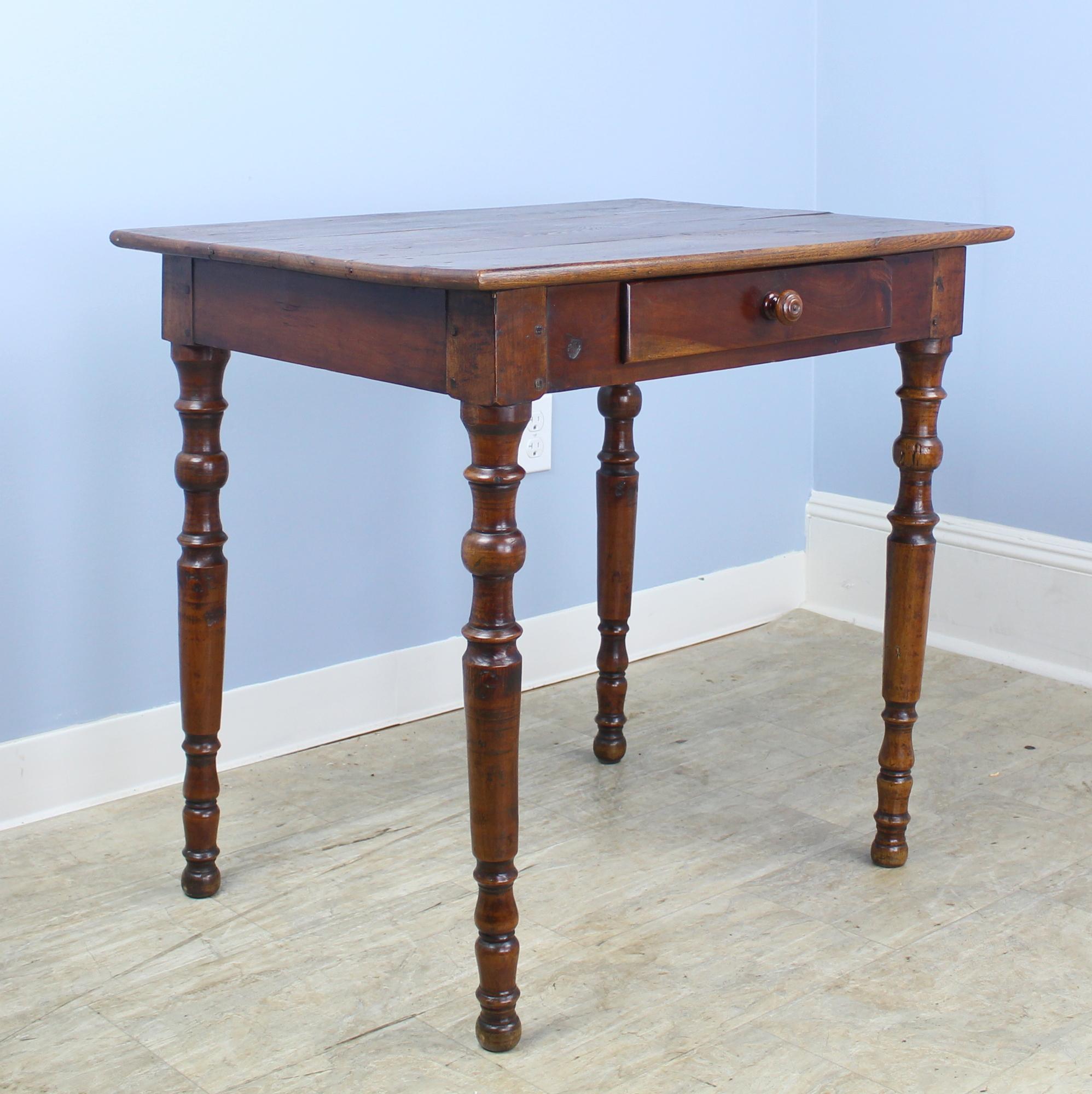 Beautifully grained ash side, lamp, or occasional table with glossy turned legs. The top is in very good antique condition and the color and patina are very good. Slight warp to front left leg does not affect the stability of the piece. No wobbling!