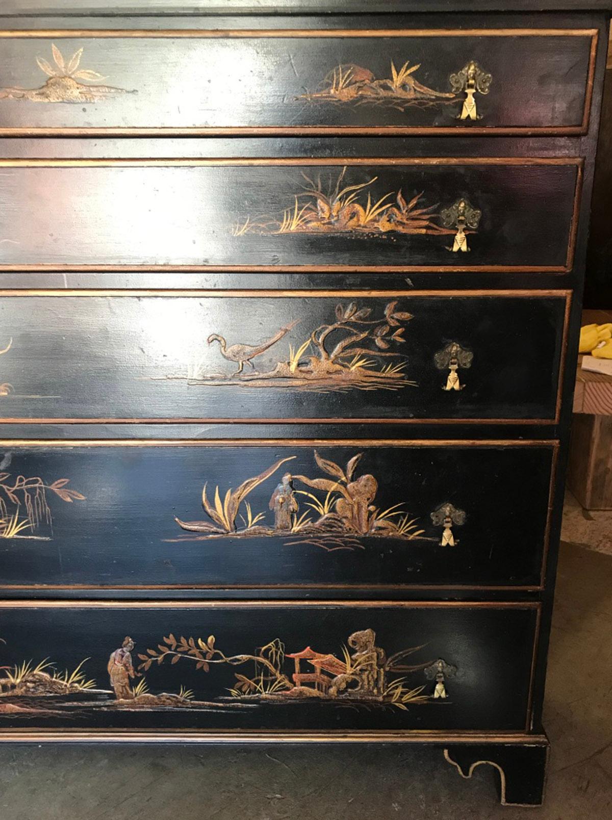 Unusual chinoiserie chest of drawers as it is only 13 inches deep. Five graduated drawers with raised decorated motives; pagodas, figures and nature, on a black and gilt background.
Each painted scene is different. Interior of drawers are red.