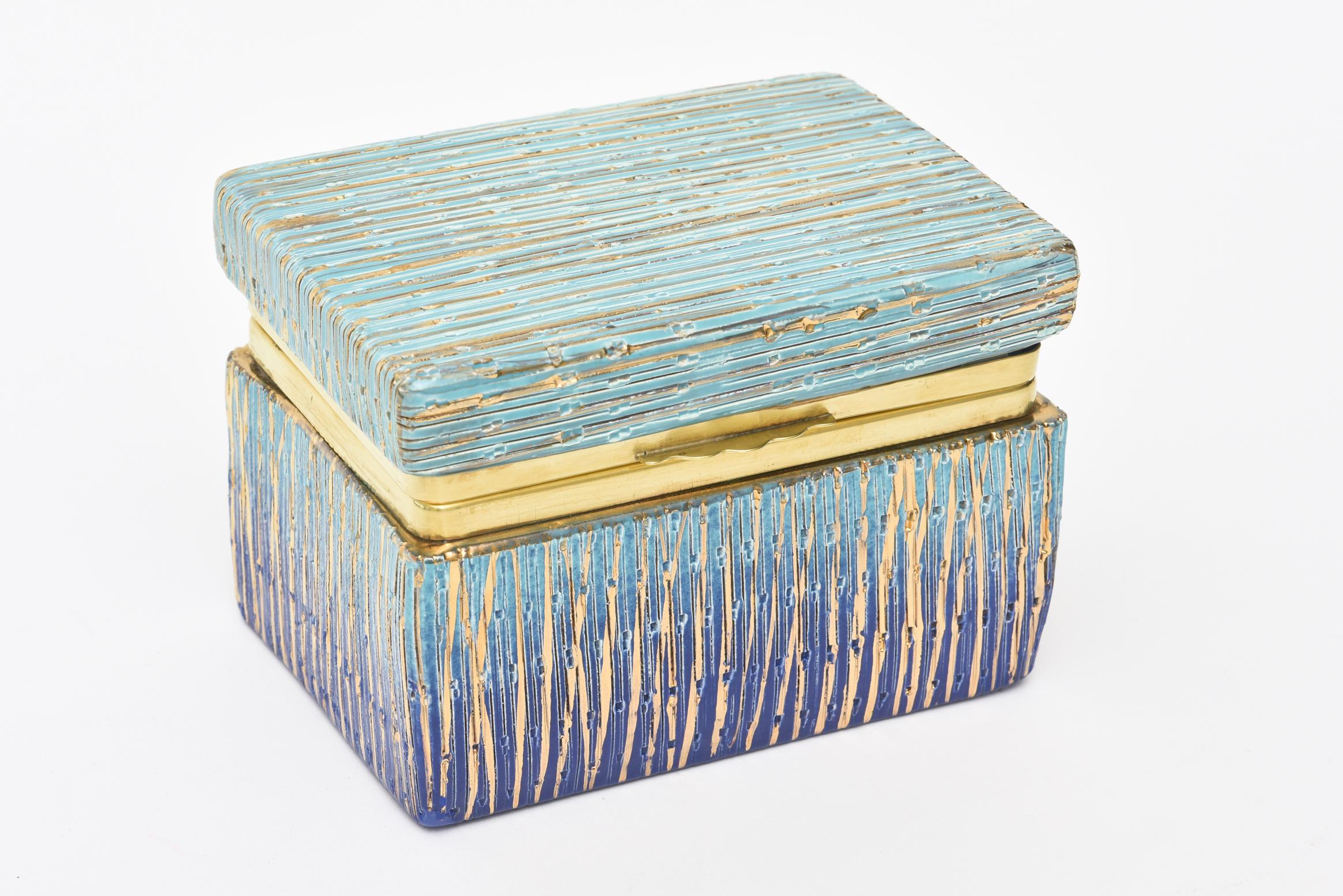 This stunning and well executed Italian Mid-Century Modern Aldo Londi for Bistossi glazed ceramic hinged box with brass rim is a real beauty. it is from the 1960s.
It has textural and dimensional lines in the glazed ceramic with painted gold. The
