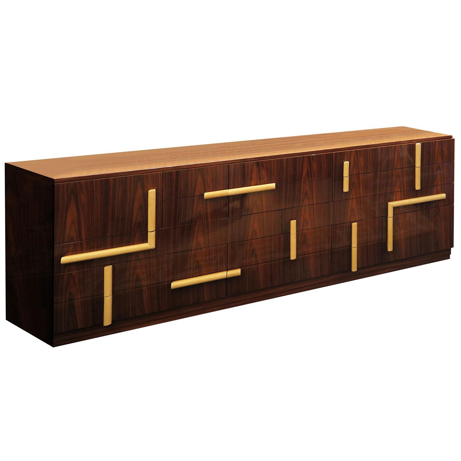 This Mid-Century Modern sideboard is done in a high gloss rosewood with cylindrical parchment handles. The piece features a puzzle design with different sized drawers and cabinets. It creates a fun and unique way to store your pieces with this