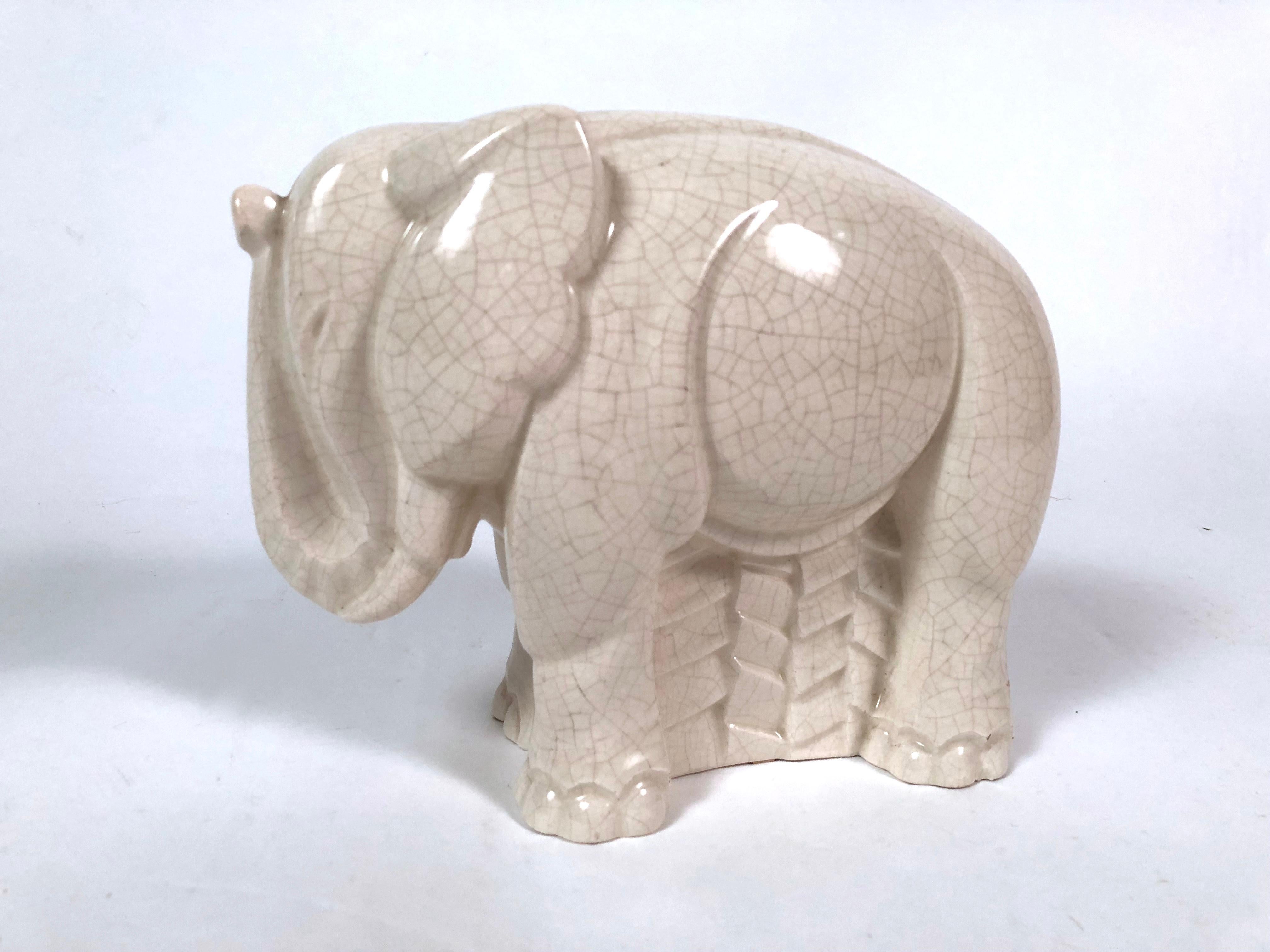 An Art Deco figure of a stylized elephant, with geometric decoration and cream crackle glaze.