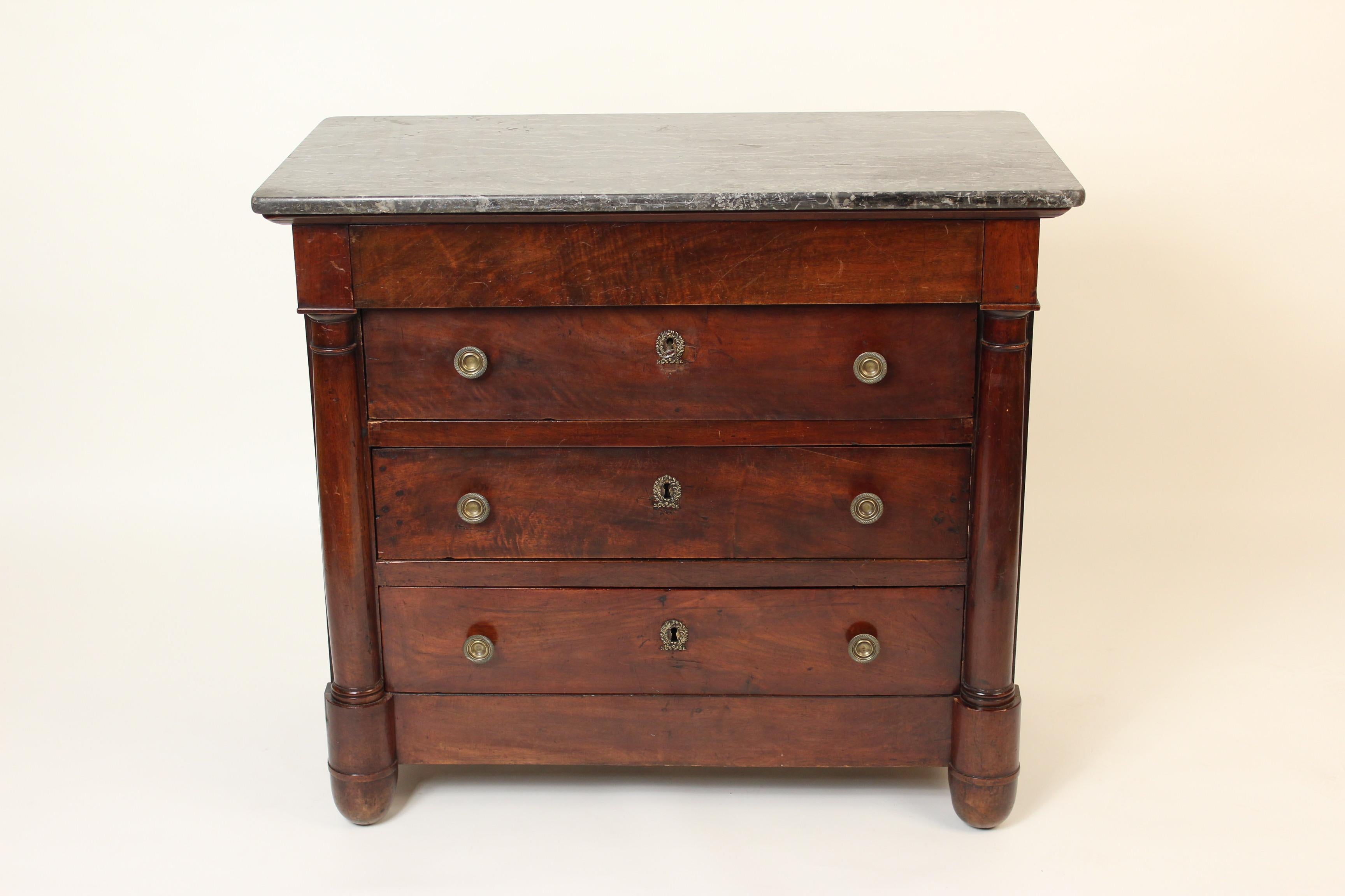 Period Empire mahogany chest of drawers with marble top and brass hardware, circa 1815. Old, probably original grey marble top, crotch mahogany drawer fronts, half columns flanking drawers, gouilloche design brass pulls and wreath form escutcheons.