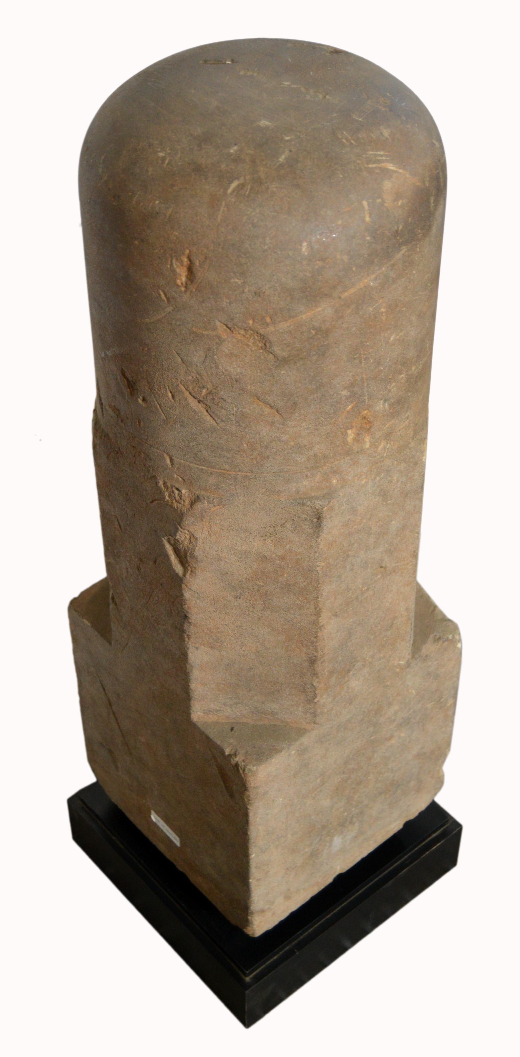 A large carved stone lingam sculpture, possibly Khmer, 13th century, Angkor period, representing the Hindu God Shiva mounted on a base. This statue is made of a square section in its lower part below an octagonal middle and a curved circular top.