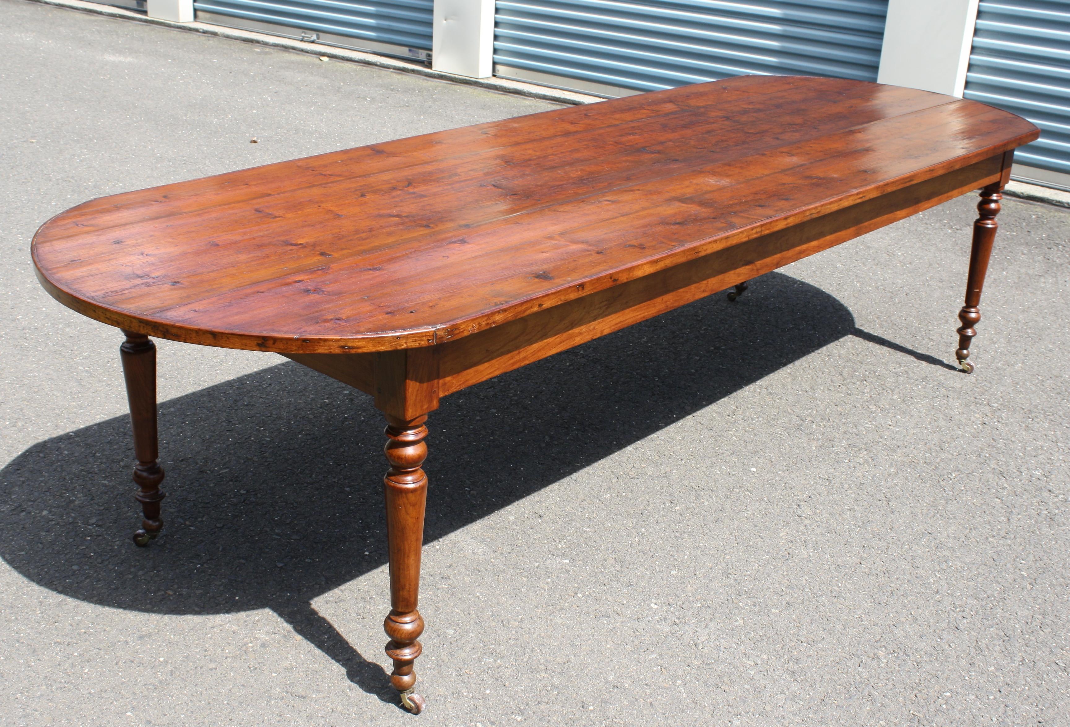A rare and highly unusual demilune-ended farmhouse or refectory table, on four Sheraton-esque turned and castered legs. Accommodating 12 for dining with minimal interference of table legs and 24 inch frieze height, it appears to be of Middle