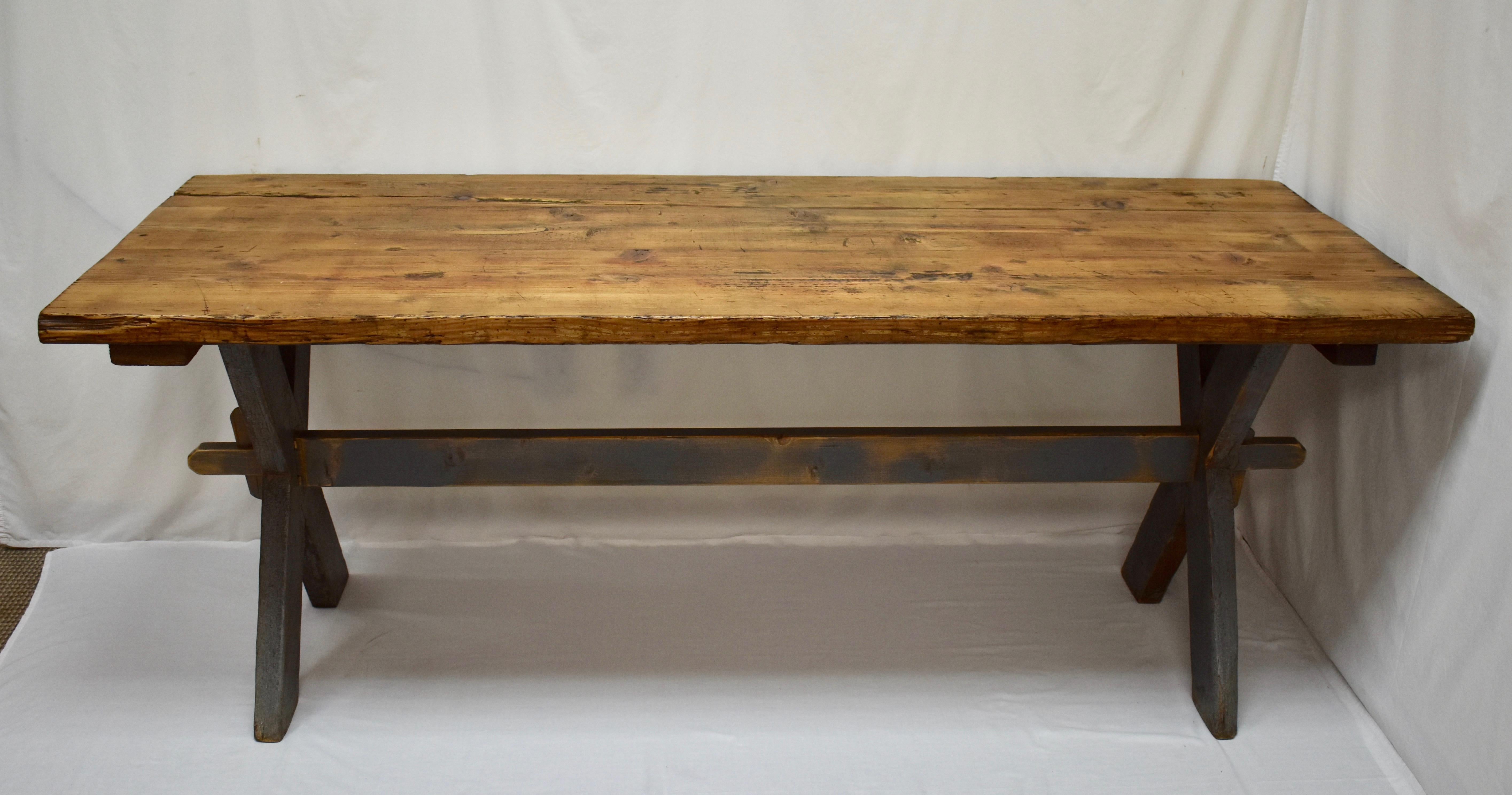This is a great old rustic trestle table with lots of character. The three board top, almost two inches thick, is magnificently gnarled, scratched and scraped with some significant chips to the edges and one old crack that has worn into a channel
