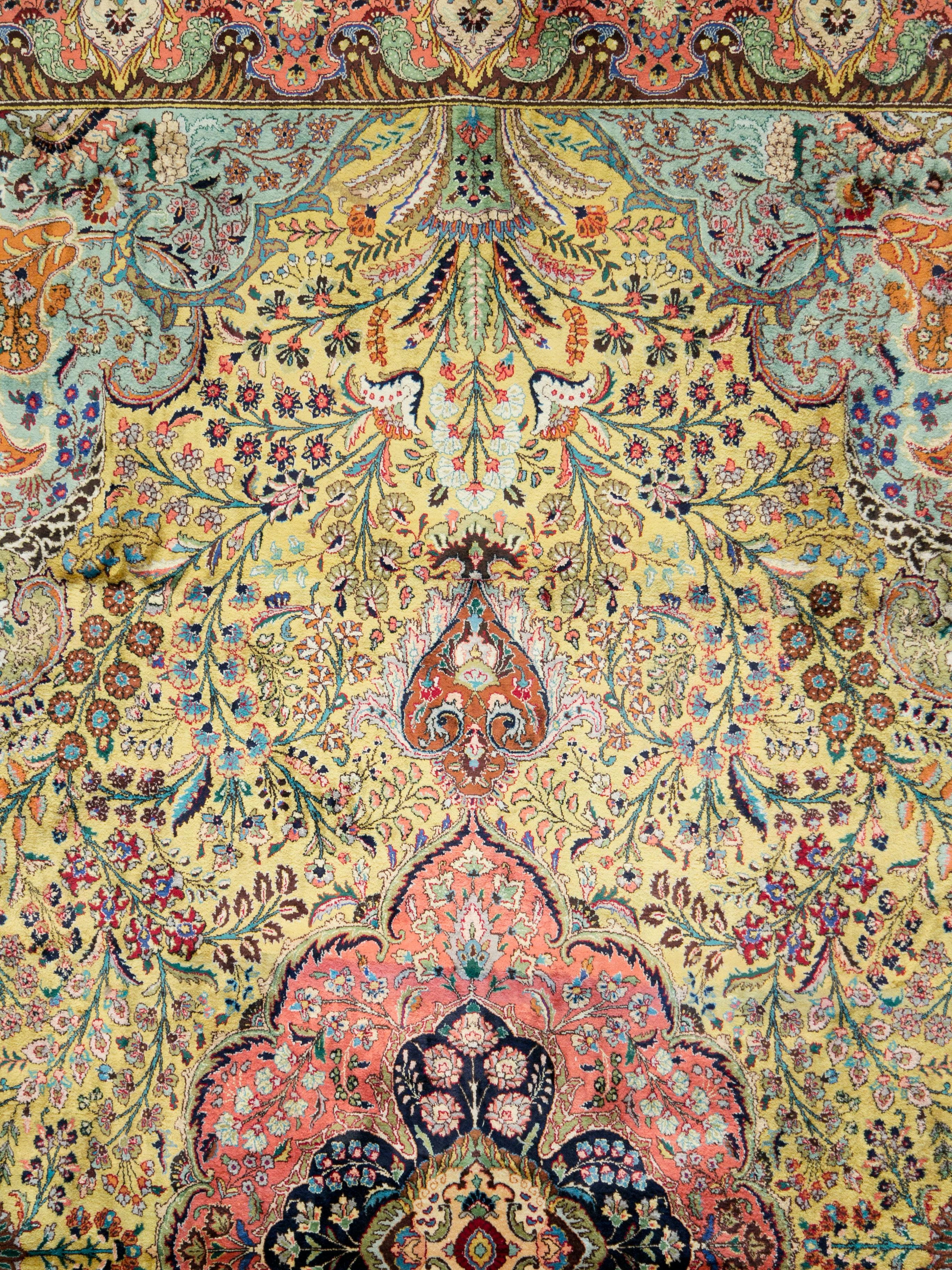 A vintage Persian Qum silk carpet from the mid-20th century. An extremely intricate pattern in a 'horror vacui' style with a wide color palette gives this Qum a very opulent look. Its long silk pile and finely knotted silk foundation feels soft to