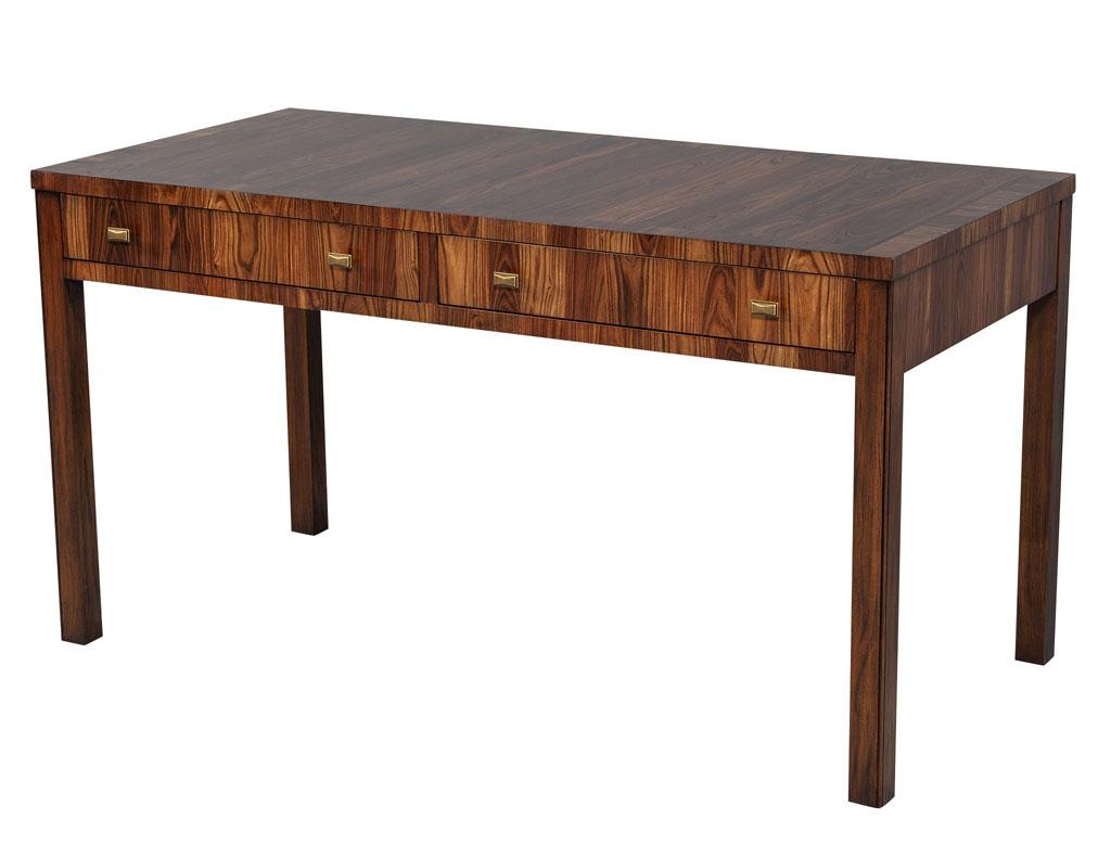 Mid-Century Modern inspired writing desk table. This desk made in North Carolina is composed entirely of solid woods. It features stunning rectangular brass handles that open two large and functional drawers. On each corner are four sleek and