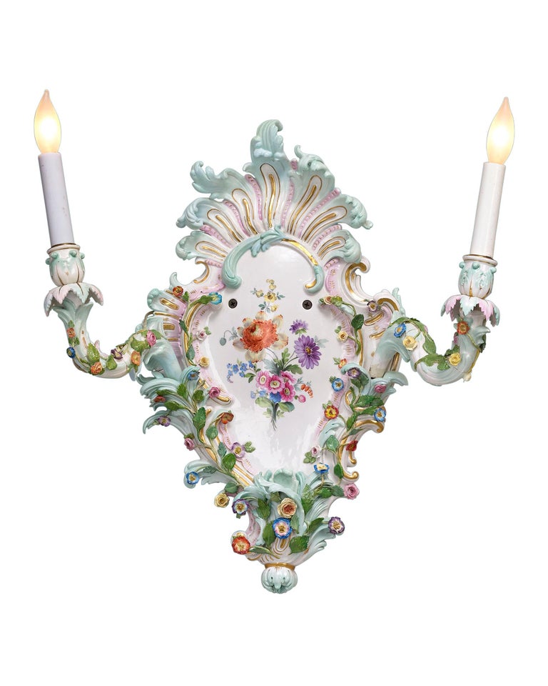 This remarkable pair of Meissen wall sconces is crafted with all of the exquisite detail and splendor of the Rococo period. Exquisitely hand-painted with gilt accents, each fixture is adorned with elaborate, classic Rococo decoration, including a