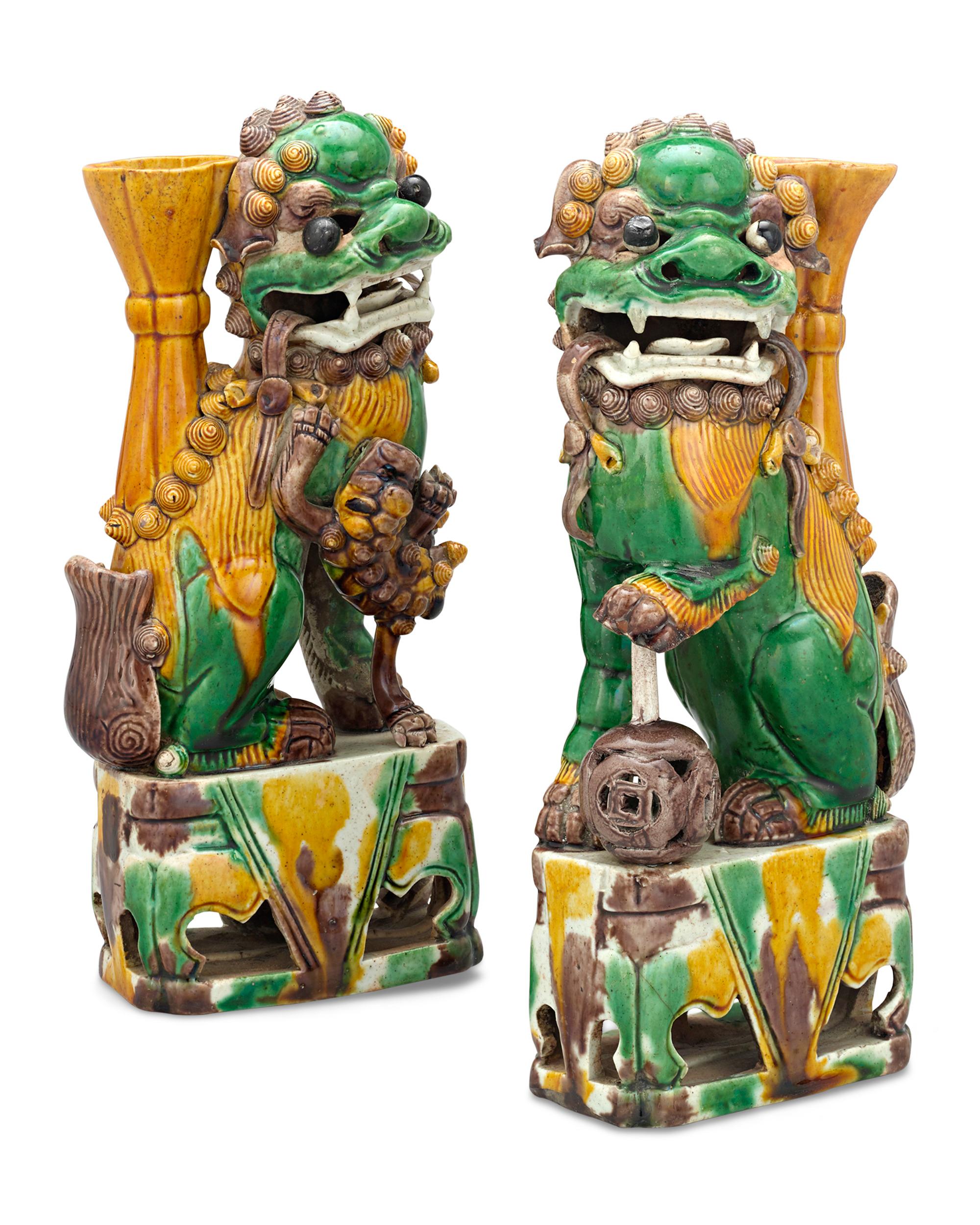 Symbolic of the Chinese concept of yin and yang, this pair of polychrome foo dogs represent totems of protection and prosperity. The female (yin) and male (yang) foo dogs are crafted in the sancai style, a popular type of decoration using glazes in