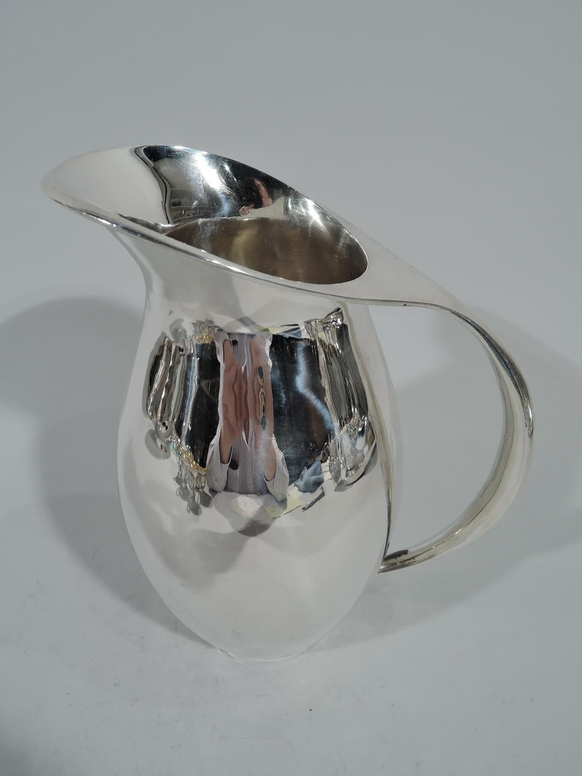 Mid-Century Modern sterling silver water pitcher. Classic form comprising ovoid body and asymmetrical mouth flowing into a sleekly tapering scroll handle. Mexican hallmark and maker’s stamp for Avanti, who was active from around the 1930s-1960s.