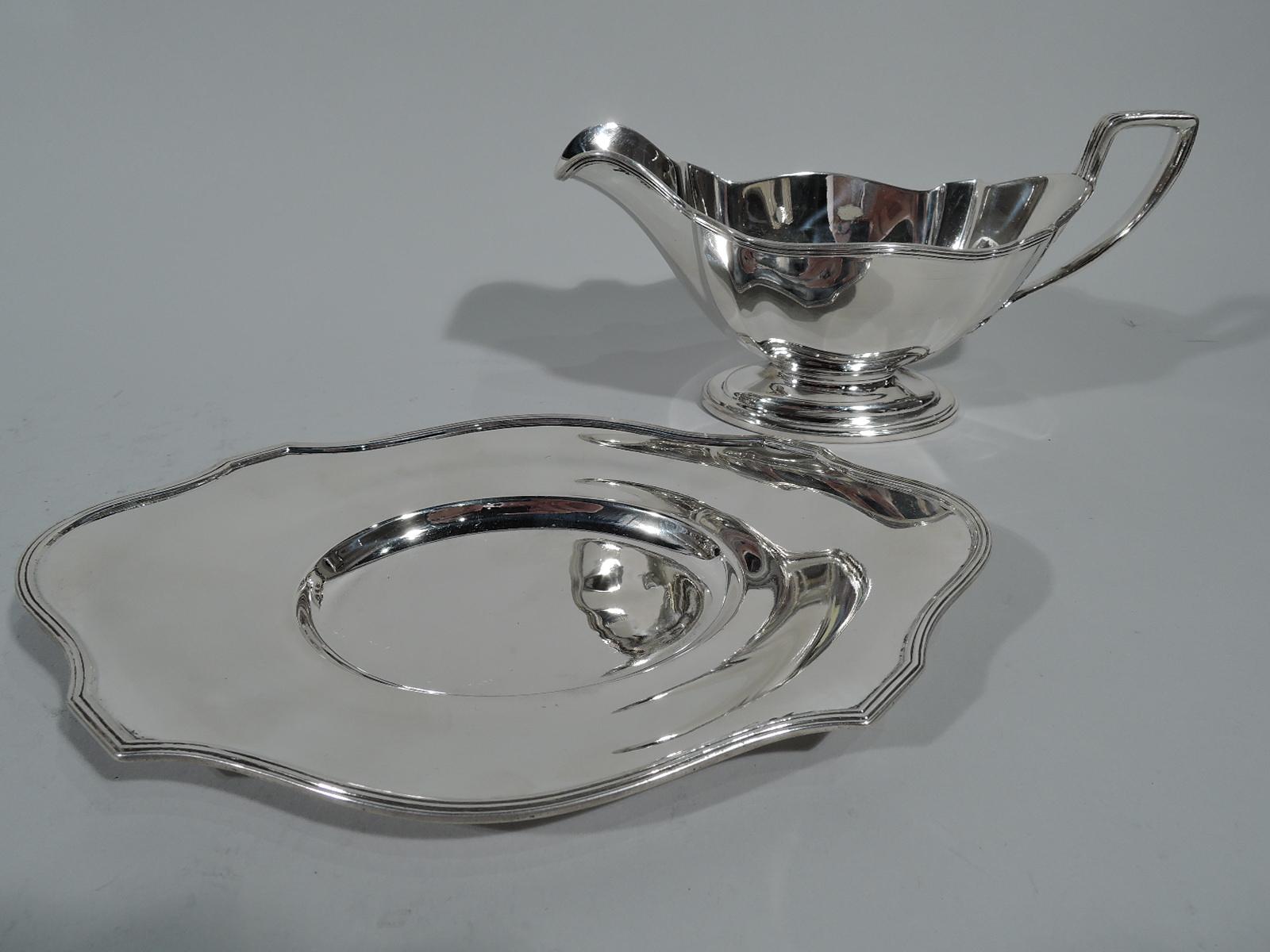 Sterling silver sauceboat on stand in Plymouth pattern. Made by Gorham in Providence in 1907. Sauceboat: Reeded helmet mouth, reeded scroll bracket handle with foliate mounts, and oval stepped foot. Date June 10, 1908 engraved on foot underside.
