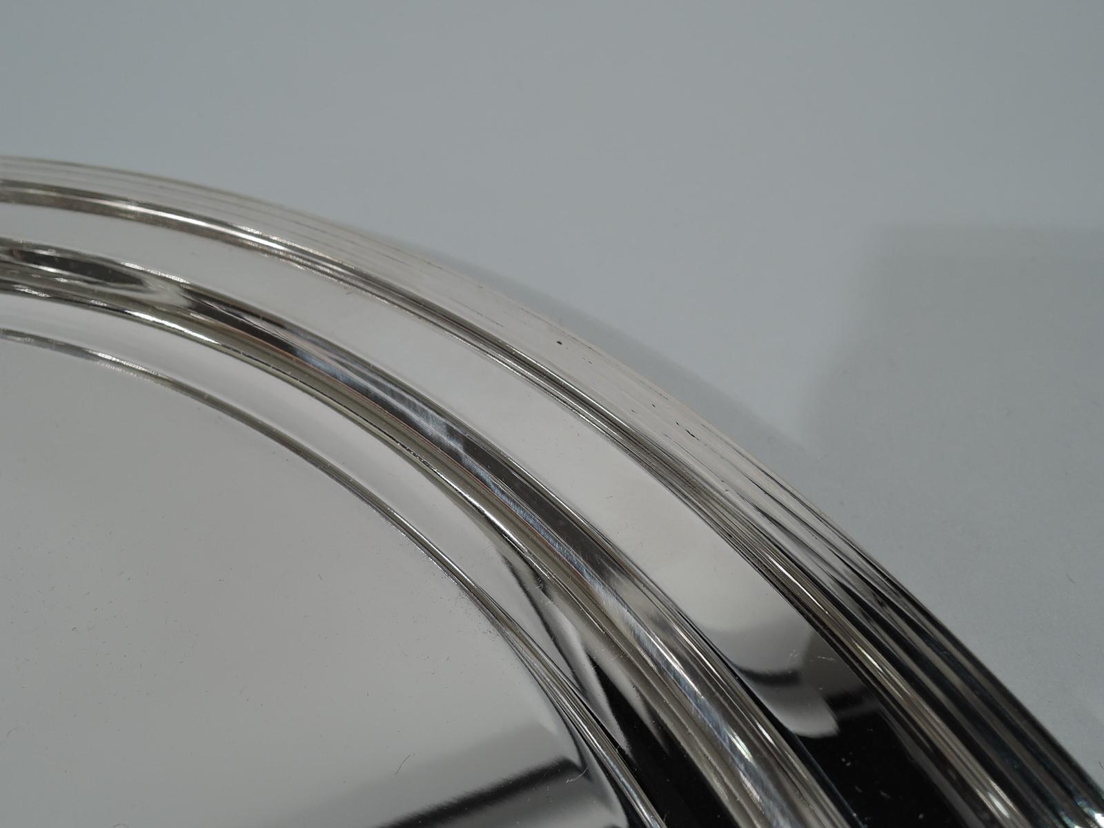 Mid-Century Modern sterling silver serving tray. Made by Tiffany & Co. in New York. Circular with well and reeded rim. Spare and practical. Hallmark includes postwar pattern no. 25218. Heavy weight: 31 troy ounces.