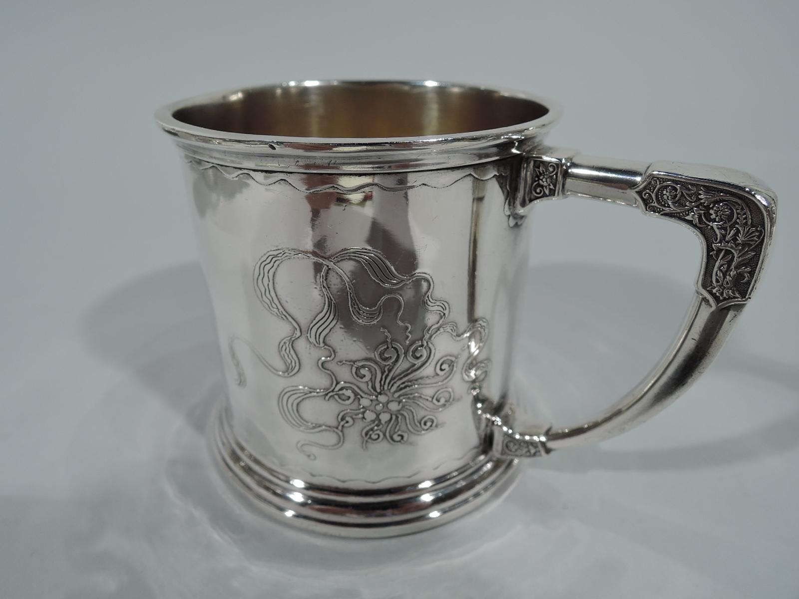 Stylistically advanced Art Nouveau sterling silver baby cup. Made by Whiting in New York, circa 1900. Drum form with spread foot and scroll bracket handle. Stylized and fluid acid-etched ornament with flowers and ribbon between scalloped borders. An
