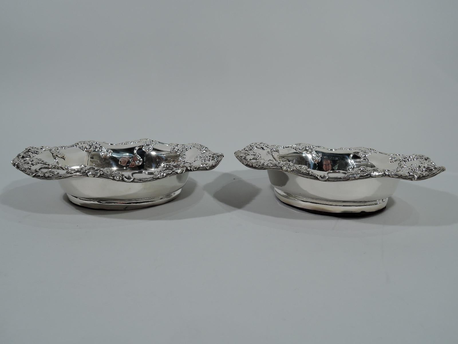Pair of sterling silver wine bottle coasters. Made by Theodore B. Starr in New York, circa 1900. Tapering sides and wavy vine rim with applied grape bunches. Well stained, turned, and felt-lined wood. Hallmark includes maker’s stamp and no.