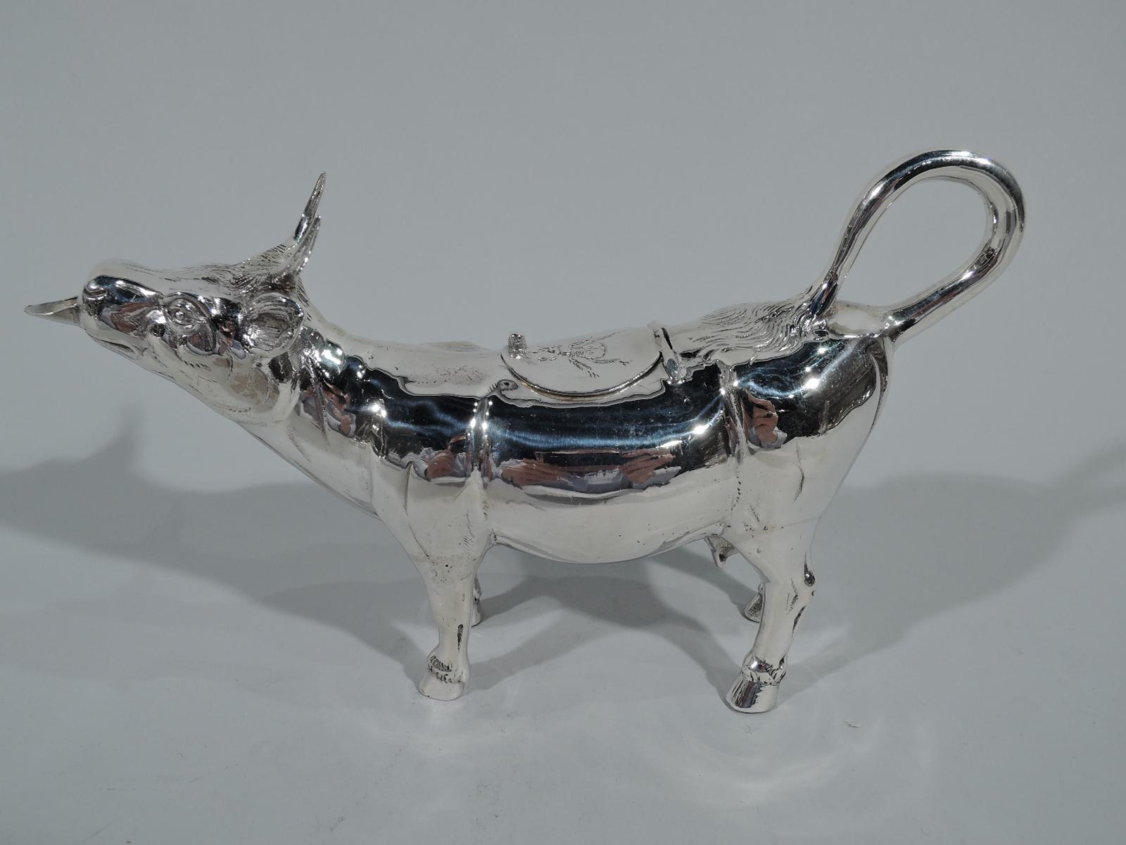Antique German sterling silver cow creamer. Wide body with firmly planted hoofs, flicked-back tail ring handle, and hinged dorsal cover with engraved fly. Head has sharp horns and flicked back ears as well as spout in form of stuck-out tongue. An