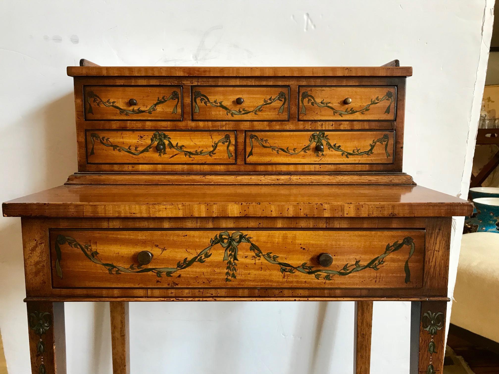 Pretty and petite Edwardian style dressing table or desk having three small drawers on top of
two and a single larger drawer under the writing surface. Hand-painted garlands decorate the front of the drawers.
Measures: 25.75” H opening from floor