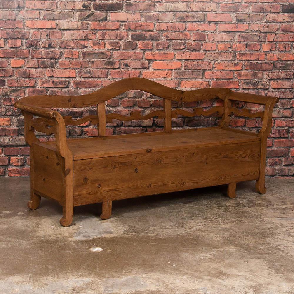This lovely pine bench is a wonderful example of Swedish country craftsmanship in the Karl Johan design and period. The gentle curve of the arms and lovely carved details add to its allure. The seat opens to reveal storage space below. Note in the