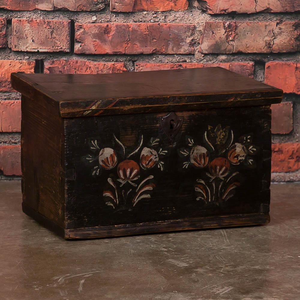 The delightful hand-painted floral motif seen on this small trunk or box was a traditional Folk Art style in the 1800s throughout Europe. Accent colors of red, eggshell and green are still seen in the flowers painted on the front panel. The entire