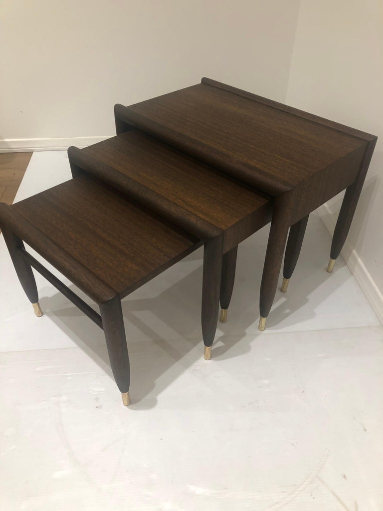 Beautiful set of three nesting tables designed by John Keal for Brown Saltman Solis mahogany, with solid polished brass tips freshly refinished in chocolate finish.