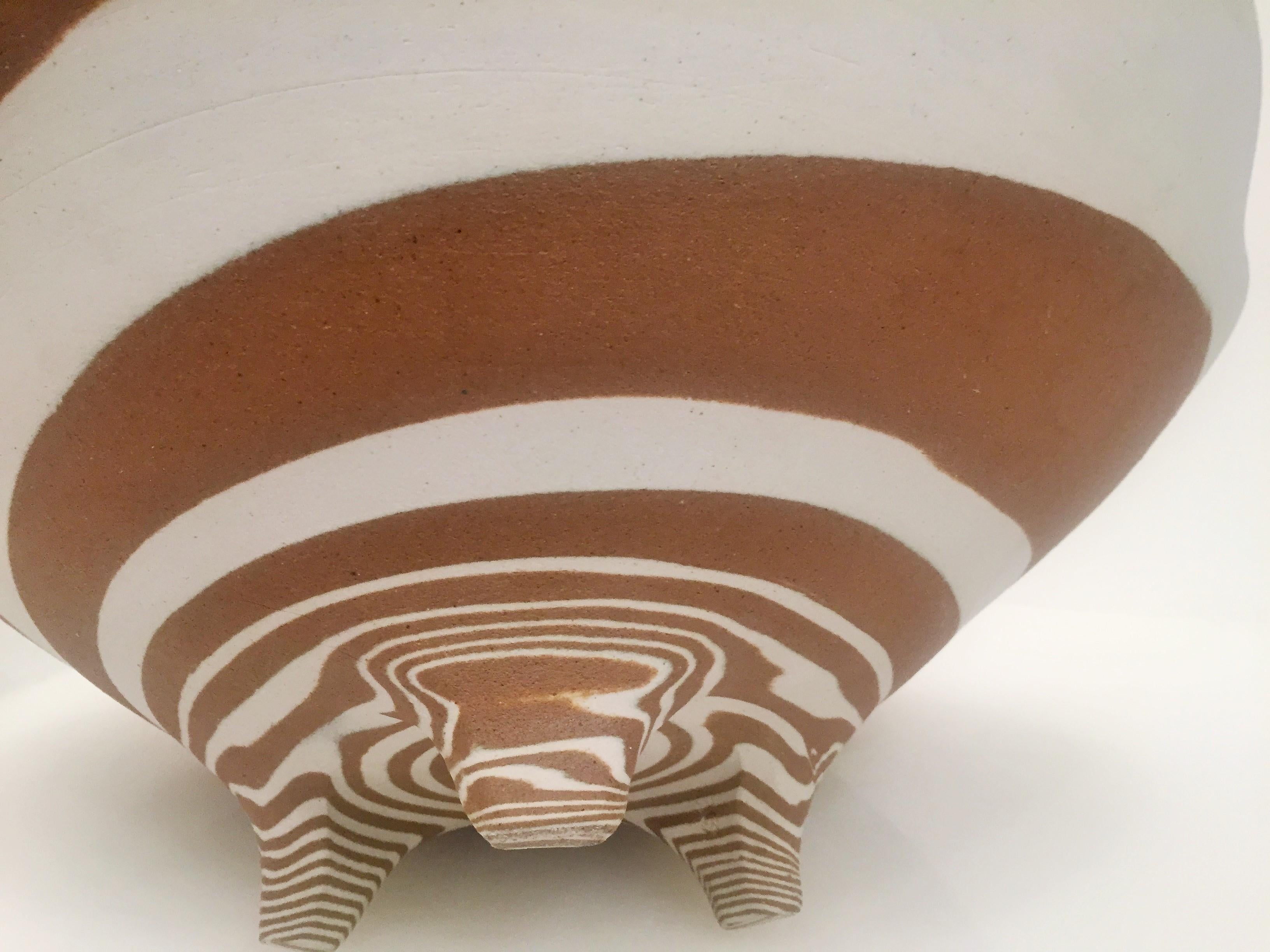 Japanese three-footed ceramic bowl. Made with brown and tan clay, with a beautiful and uneven swirl. The edge of the bowl mimics an abstract rosette. The swirl is even more magnificent when seen from below, which makes the bowl interesting from
