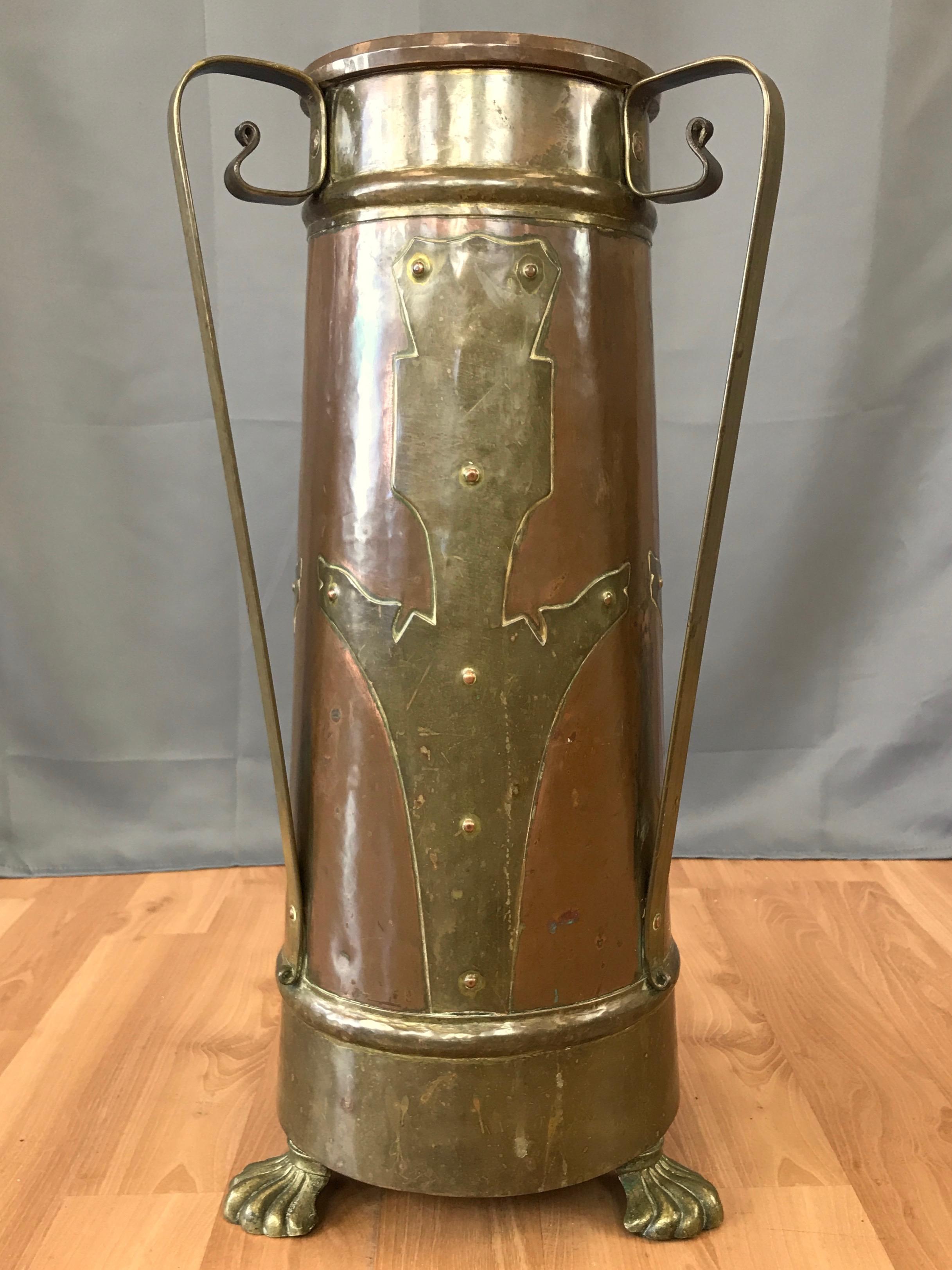 A commanding turn of the century Arts and Crafts movement copper and brass umbrella and walking stick stand.

Handsomely done metalwork on display throughout, starting with a slightly tapered heavy cylindrical copper body featuring wide brass bands