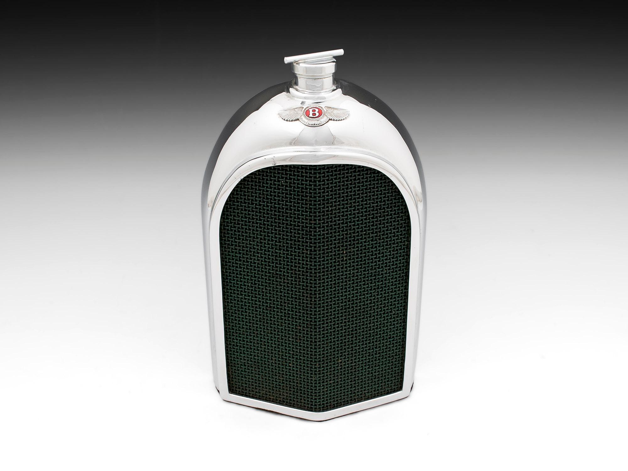 Stunning Bentley radiator spirit decanter. Heavy chromium-plated metal around a glass container with green mesh grill. 
There is a slot at the back to view its contents and a baize cloth on the base. 
The small red enamel Bentley badge and screw