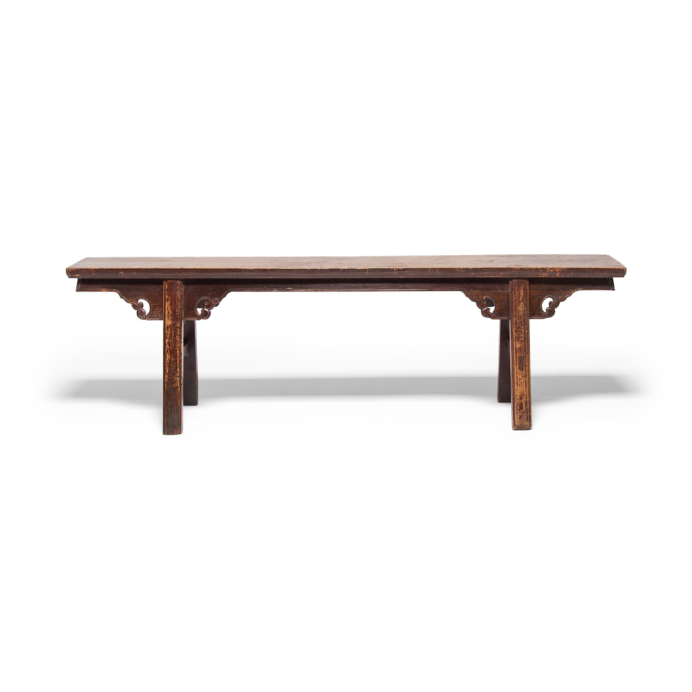In most Qing dynasty homes, stools and chairs were the only form of elevated seating, and a bench such as this would have been found at a temple or public theater. This 19th century walnut bench has splayed legs linked by straight double stretchers