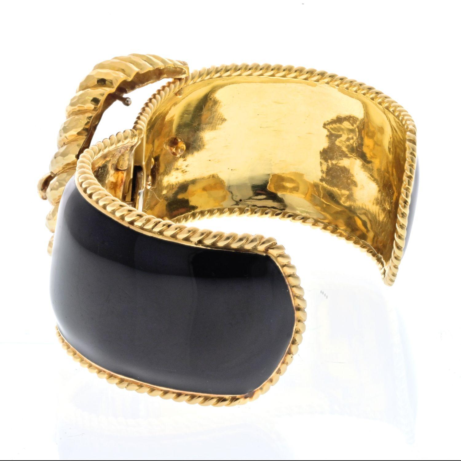 The David Webb 18k yellow gold cuff bracelet is a stunning piece of jewelry that exemplifies the brand's signature craftsmanship and unique design. Fashioned as an anchor buckle, the bracelet showcases a remarkable blend of elegance and nautical