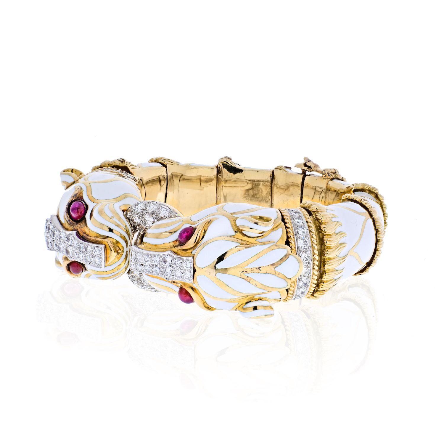 Designed as an articulated hinged bangle, the two opposing white enamel panthers, with bezel-set cabochon ruby eyes and a circular-cut diamond nose and collar, holding a circular-cut diamond hoop in their teeth, their white enamel bodies decorated