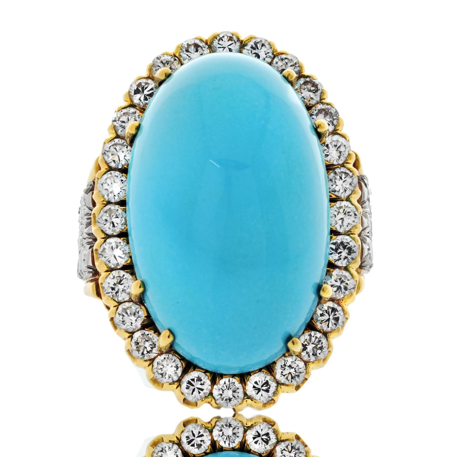 This spectacular David Webb Platinum & 18k Yellow Gold Ring is a vintage masterpiece of timeless elegance and bold design. The centerpiece is an impressive oval cabochon-cut turquoise, surrounded by a dazzling single-row diamond halo. The ring’s