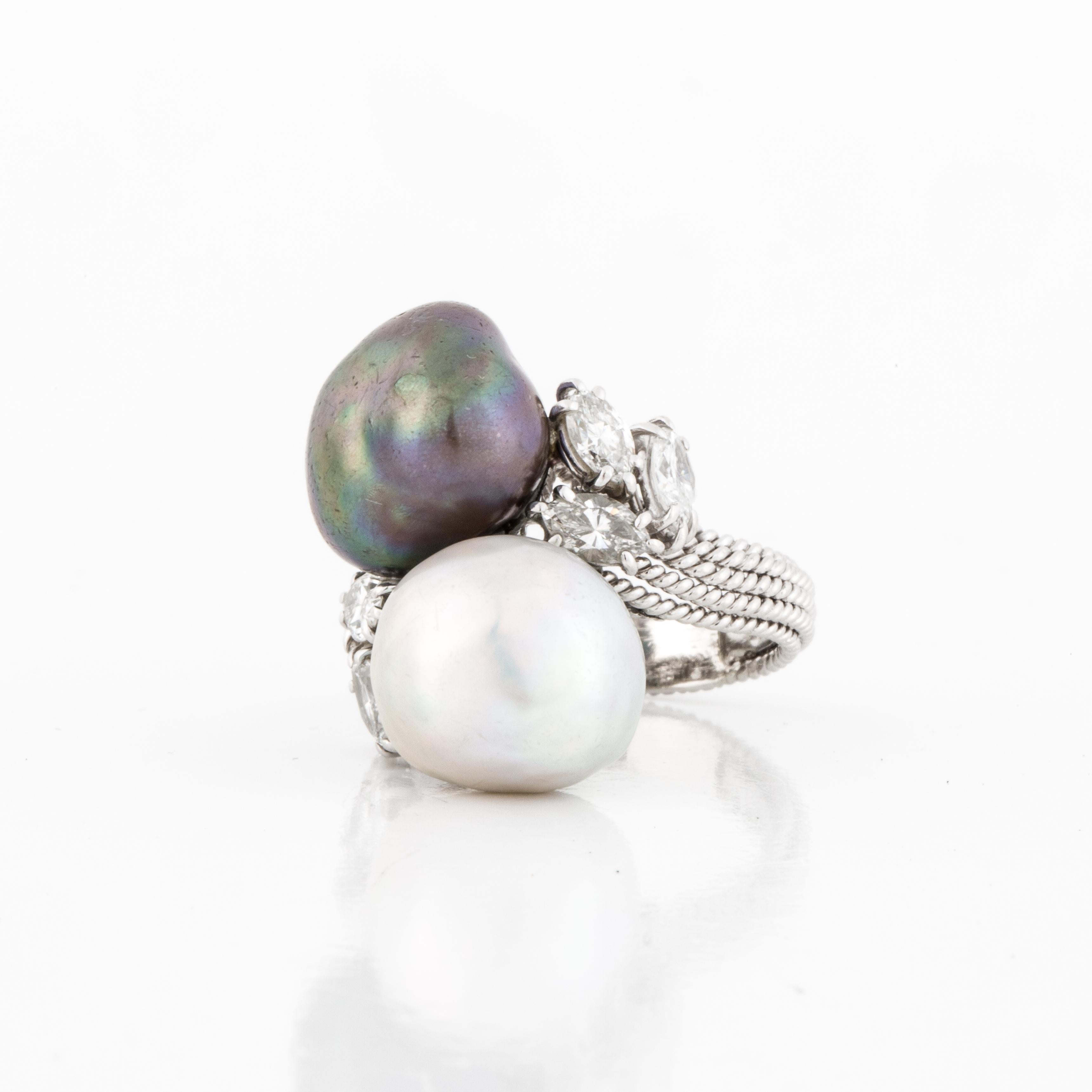 David Webb platinum ring featuring both a gray and white South Sea pearl in a bypass style.  The pearls measure 10-13mm each.  The pearls are accented with six marquise shape diamonds on both sides; F-H color and VVS2-VS1 clarity.  Ring is currently
