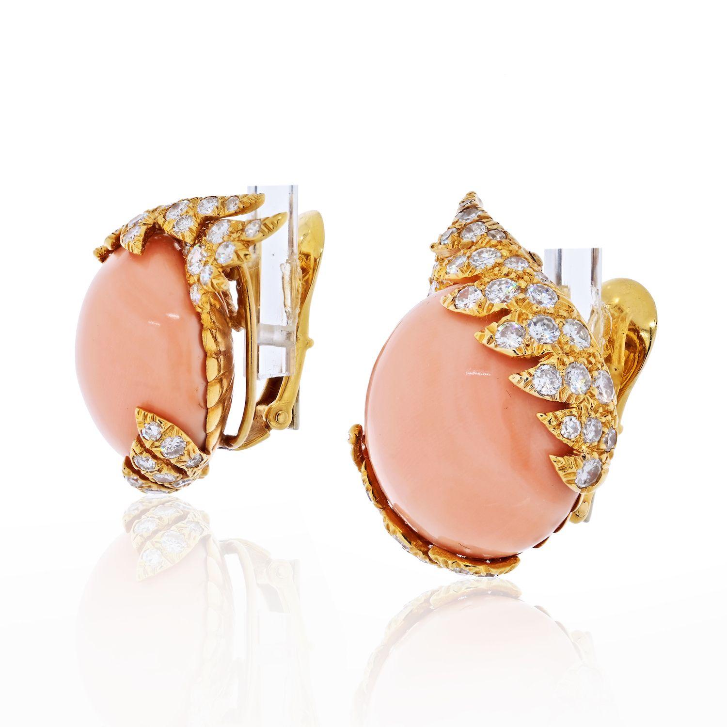 David Webb: A pair of coral, diamond and 18K gold ear clips.
Each featuring a round button cabochon coral, 19mm, surrounded by the diamond-set winged frame, weighing an estimated total diamond weight of approximately 2.10cts; completed by clips;