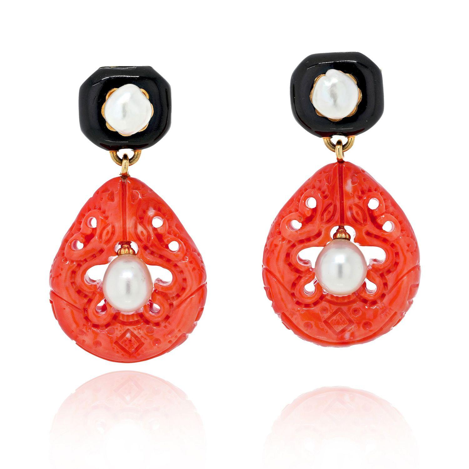 The surmounts set with two semi-baroque cultured pearls within black enameled frames, suspending carved corals centering drop-shaped cultured pearls.
Length: 2 3/8 inches. 
The coral is medium orange-pink, with a few areas of whitish mottling and