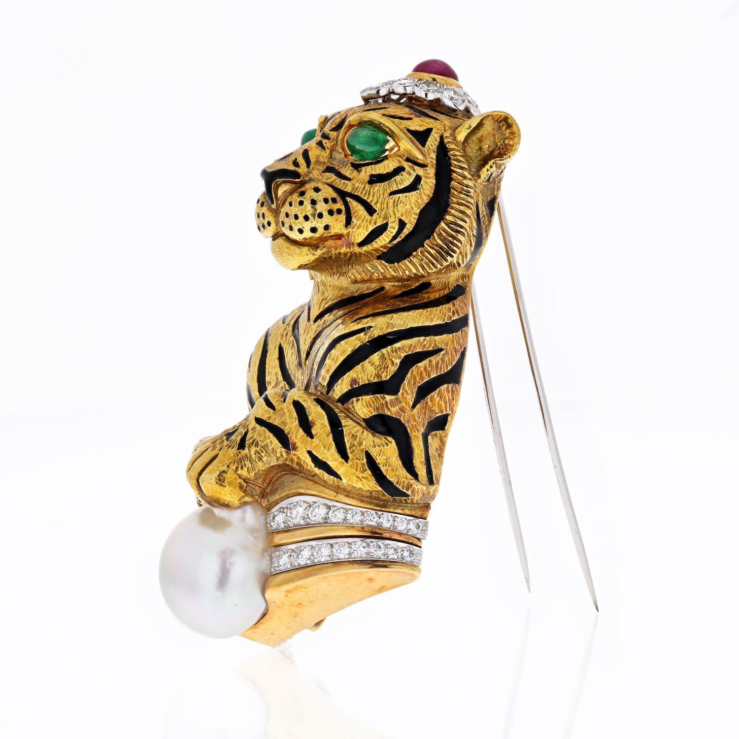 Designed as a tiger, the body decorated with textured gold fur, enhanced with black enamel stripes, with circular-cut diamonds, emerald eyes, cabochon ruby atop of the head. Tiger is holding a cultured baroque pearl, mounted in 18K yellow gold and
