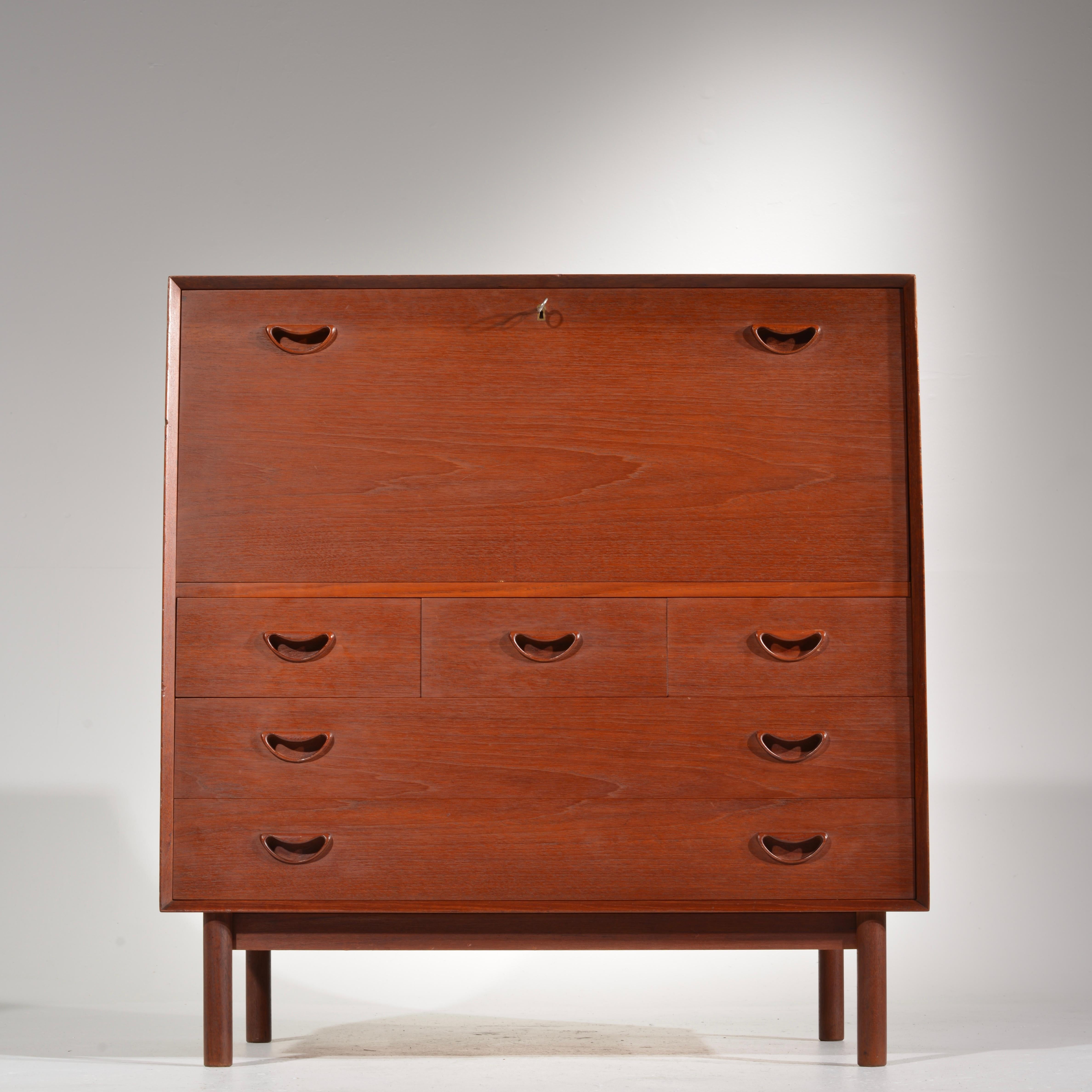 Featuring a drop down desk or bar, three smaller drawers over two large drawers. Distinctive finger jointing on top and sides. Excellent traditional oiled finish patina and rich vintage color. Imported from Denmark by John Stuart.