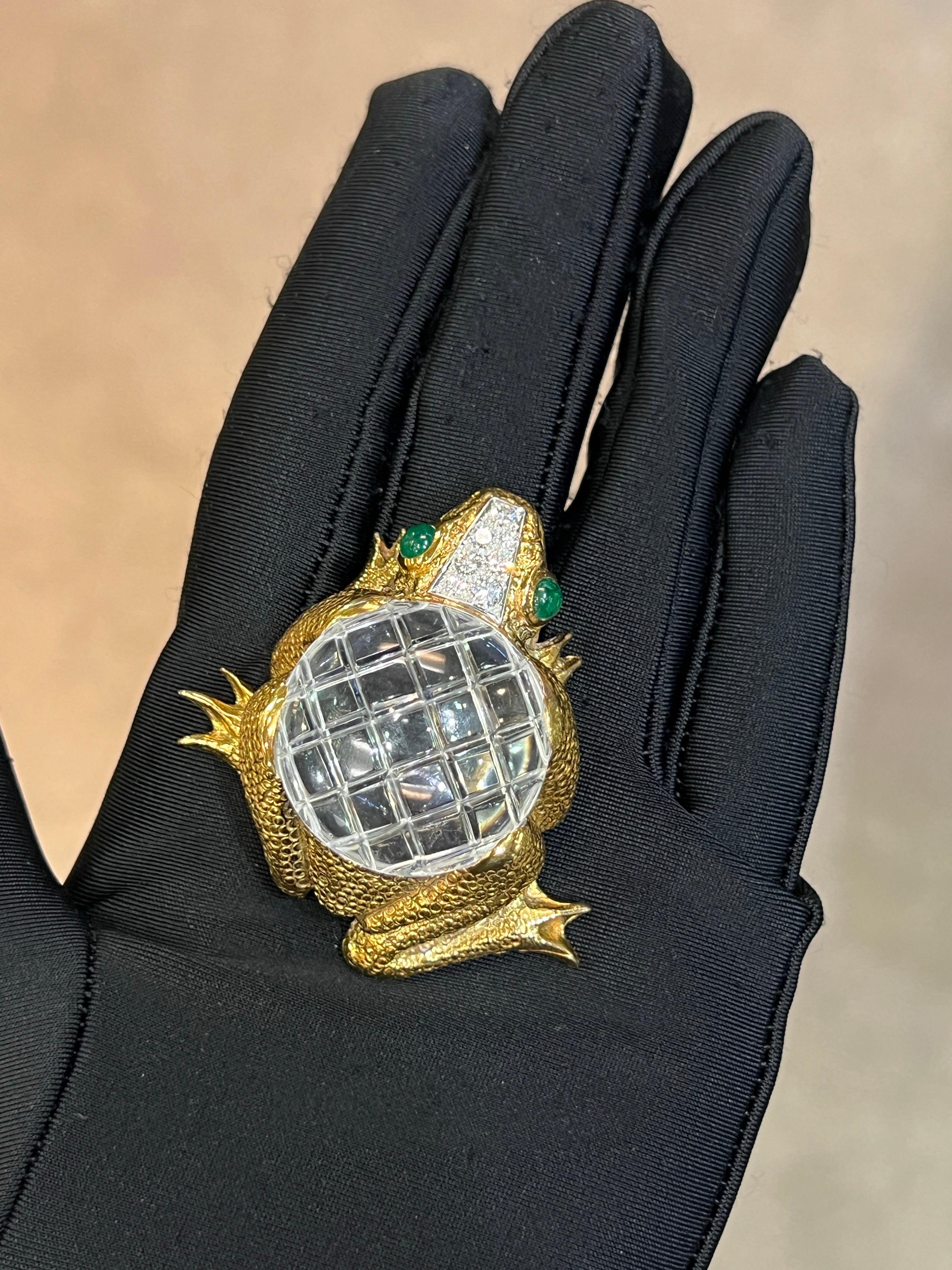 David Webb Rock Crystal Frog Pendant Brooch 

A hammered gold frog brooch that converts into a pendant featuring a round rock crystal carved with a geometric pattern on its back. The eyes are set with cabochon emeralds, and the head is adorned with