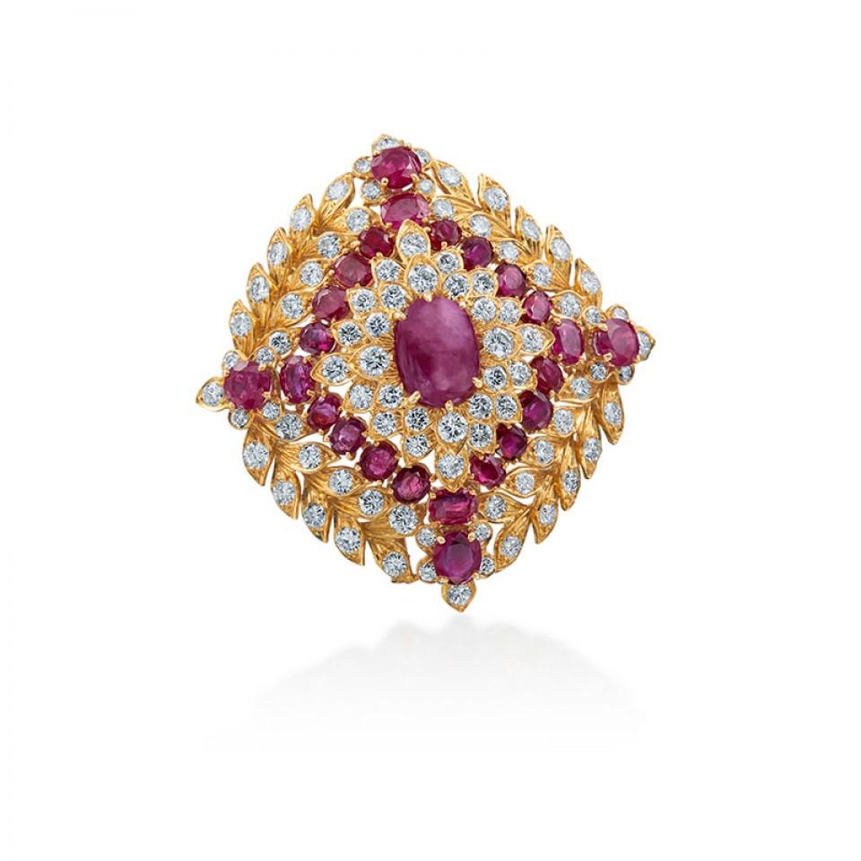 This brooch by designer David Webb is 18 karat yellow gold and platinum with an approximately 5.90 carat cabochon cut ruby as the centerpiece and surrounded by circular cut rubies weighing approximately 14.64 carats and round brilliant cut diamonds