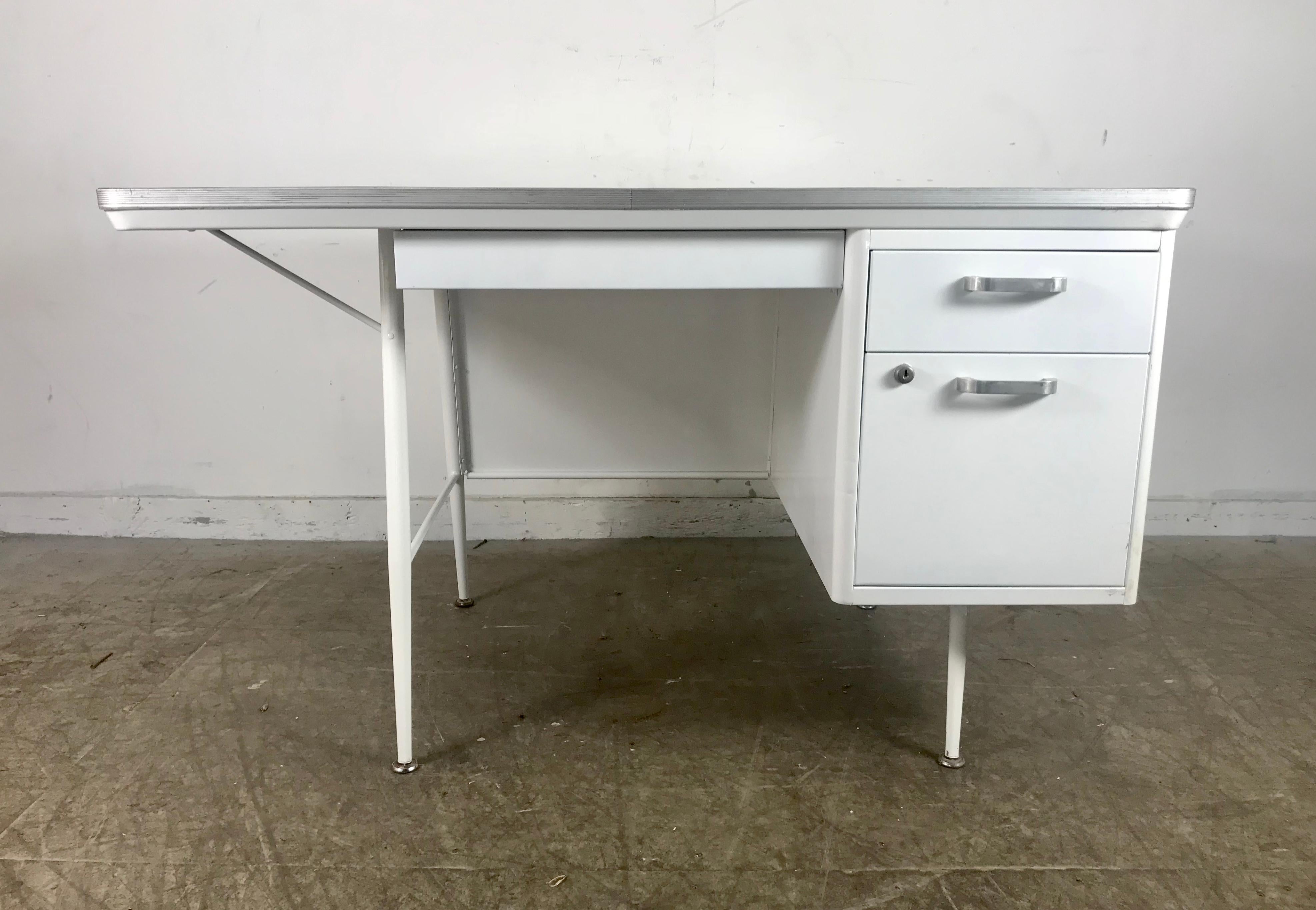 Modernist lacquered steel desk. Metal industrial. All steel industrial desk with faux wood laminate top. Fully restored and professionally lacquered in a beautiful white. Elegant and functional, featuring generous top pencil drawer, one right drawer