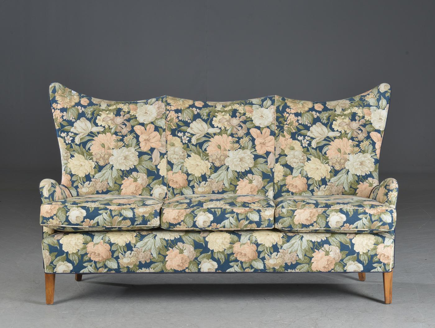 Very charming high back or wingback 1950s sofa from Denmark upholstered in a floral fabric. Sturdy construction raised on beech wood legs. Nice rolled armrests reminiscent of Carl Malmsten's designs. High back sofas have a strong presence about them