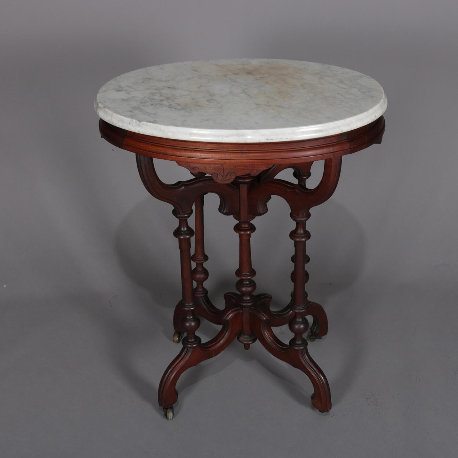 Antique Eastlake plant stand features bevelled oval marble top supported by carved walnut base having incised decorated skirt over s-scroll brackets supported by turned columns surrounding central column with upper and lower finials and raised on