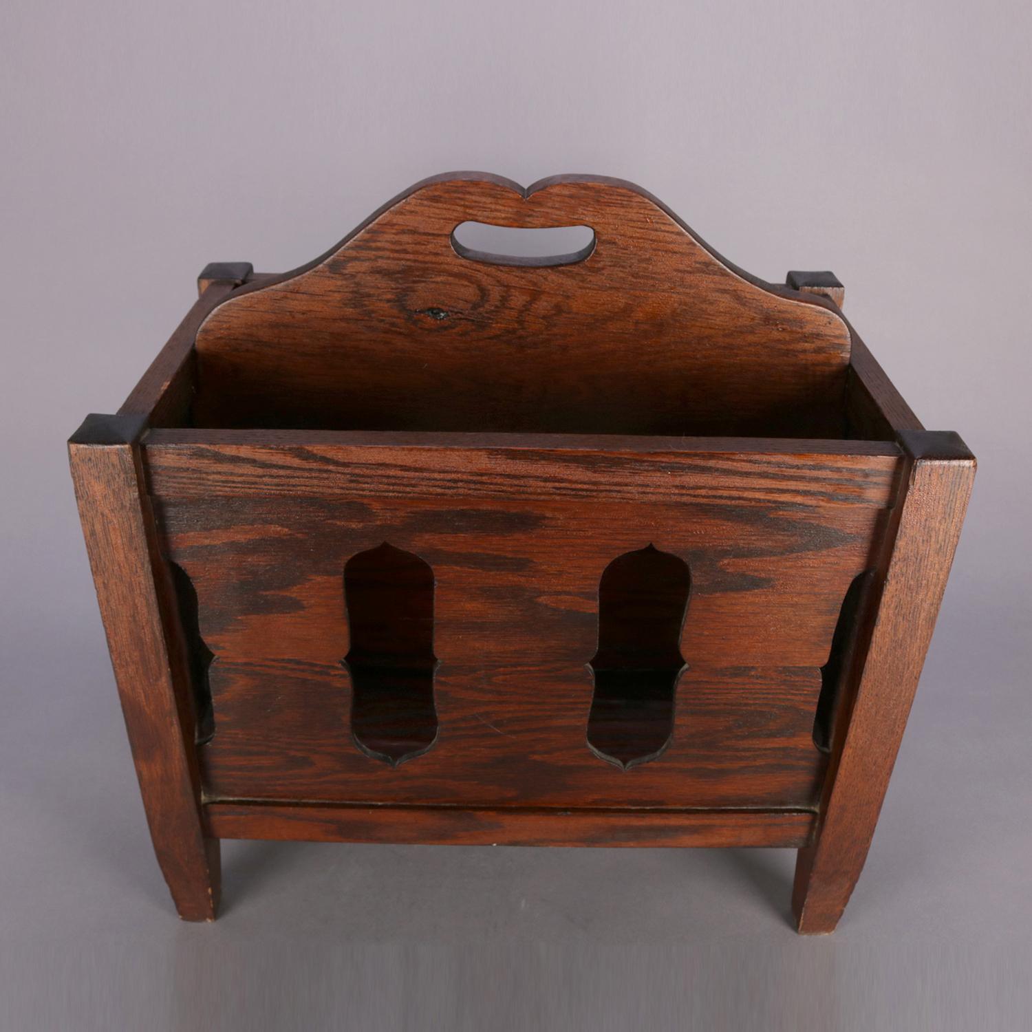 Arts & Crafts Stickley School mission oak magazine rack features quarter sawn oak construction with cut-out sides and central divider with handle, raised on square and slightly tapered legs, circa 1910.

Measures: 20