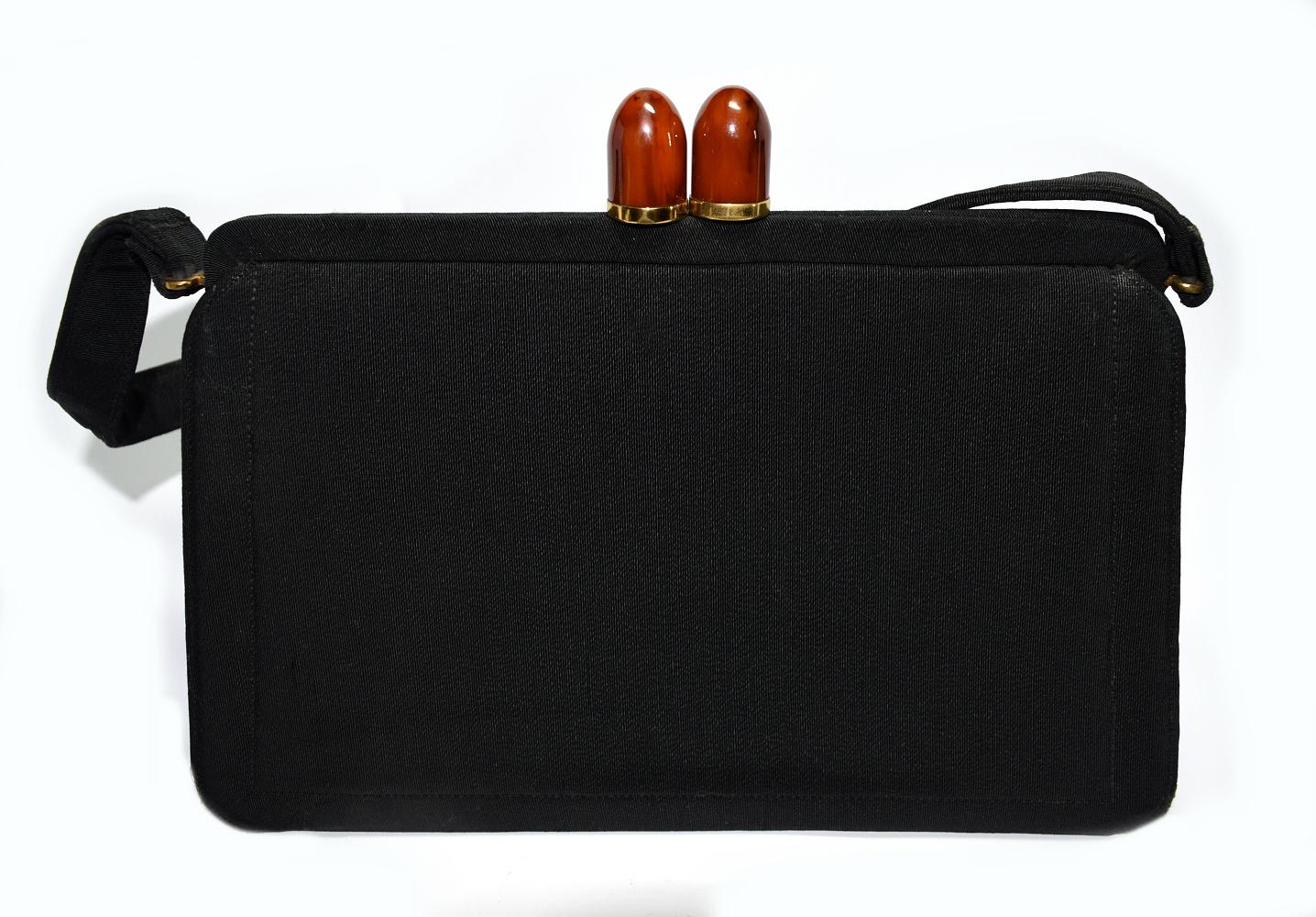 This wonderful vintage handbag was made in the 1930s-1940s for Saks Fifth Avenue in New York. The body of the bag is constructed from black grosgrain, while the kiss lock closure features a cherry red Bakelite hardware with gold-tone accents. There