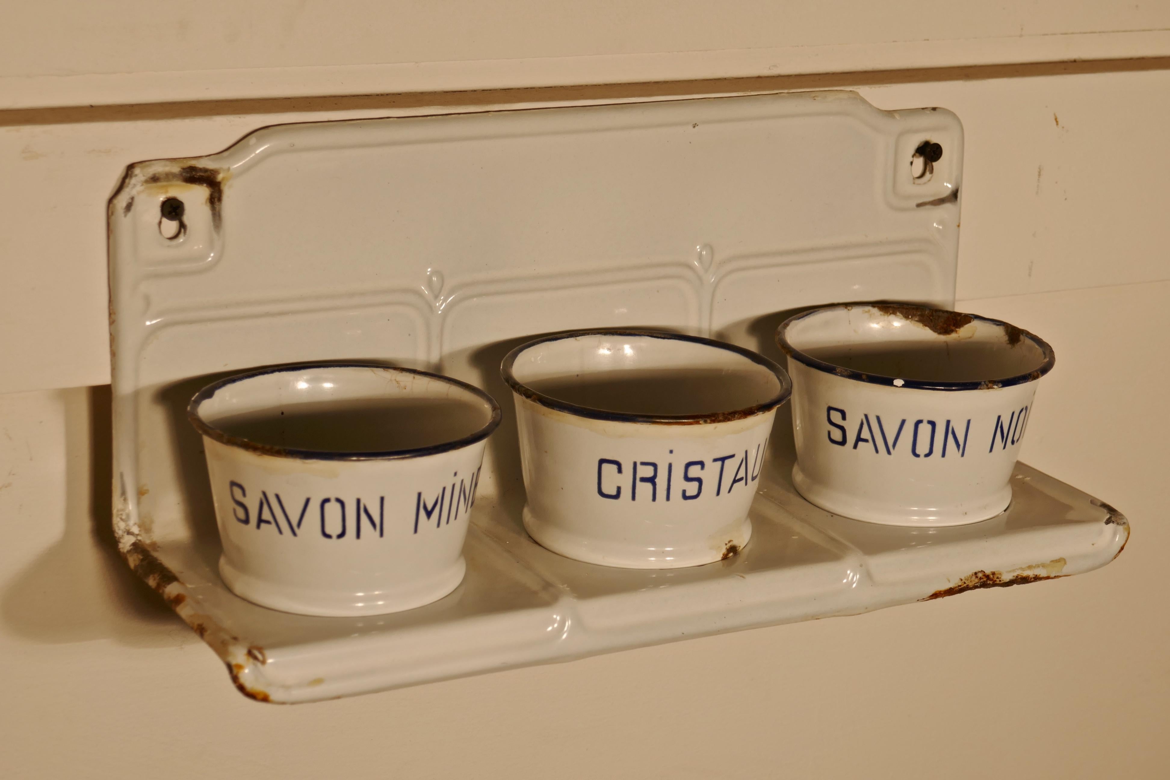 French enamel, three Canister soap dish laundry set

A good white with blue detail soap Canister laundry set in its rack, the set is complete, it has a wall hanging rack which accommodates the three soap containers, Savon Noir, Cristaux and Savon