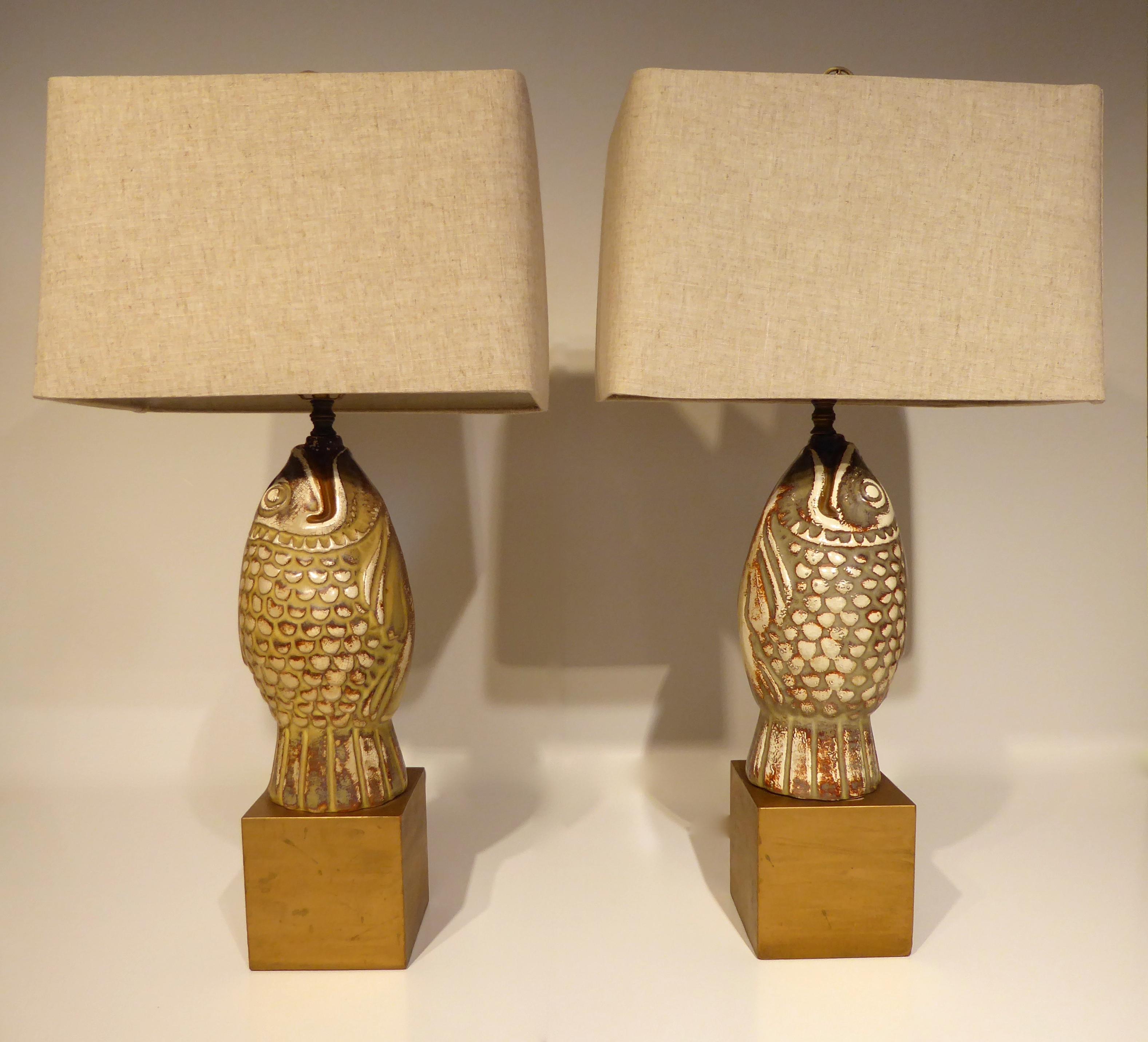 A pair of stylized ceramic Koi figures, mounted as lamps on gold painted bases, circa 1960s. The pair of Koi lamps were custom made, with the figures situated so that they are opposing (face each other). The country of origin on the ceramic parts is