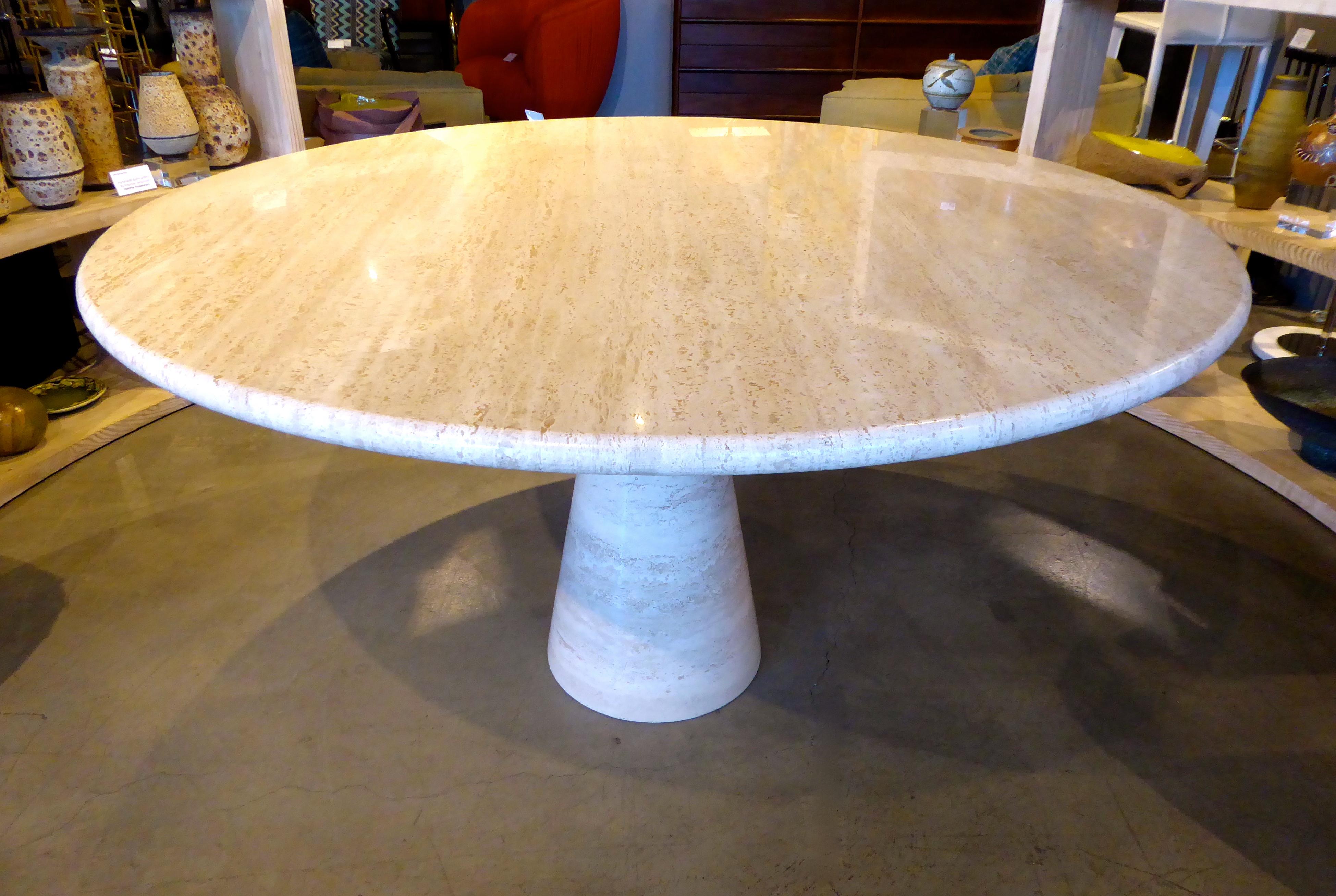 A circular Italian travertine dining table in the style of Angelo Mangiarotti, circa 1970s. The conical table base flares slightly at the top but is thicker than the delicate base on Mangiarotti table.