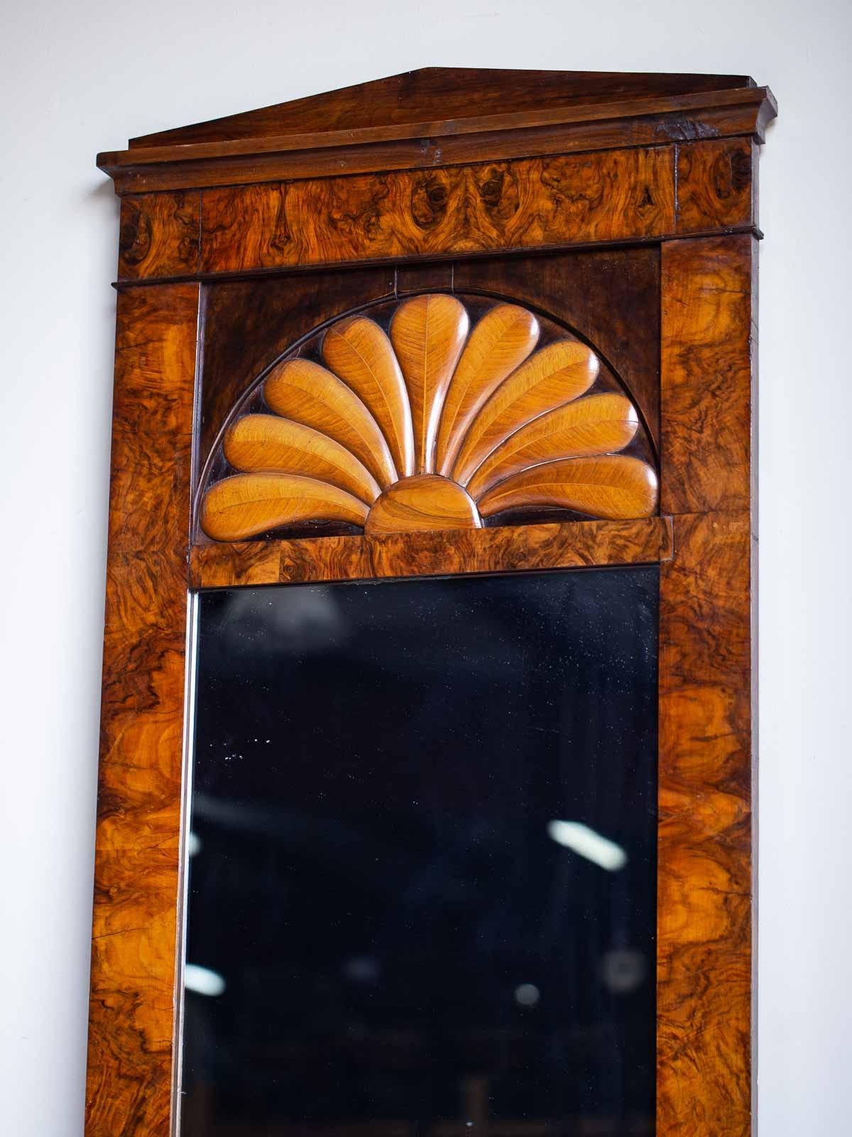 This tall Biedermeier antique German burl walnut mirror circa 1830 has a tall and slender shape and was originally placed between a pair of windows in an upscale Berlin residence. The beautiful grain of the superb walnut provides a delightful