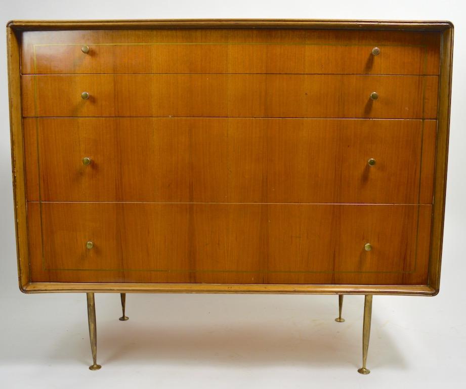 Very chic four drawer dresser in original finish, with brass inlay, pulls, and legs. The case has shaped sculpted sides which surround the drawer fronts. This chest is continental, we believe probably Italian. The case shows cosmetic wear to finish,