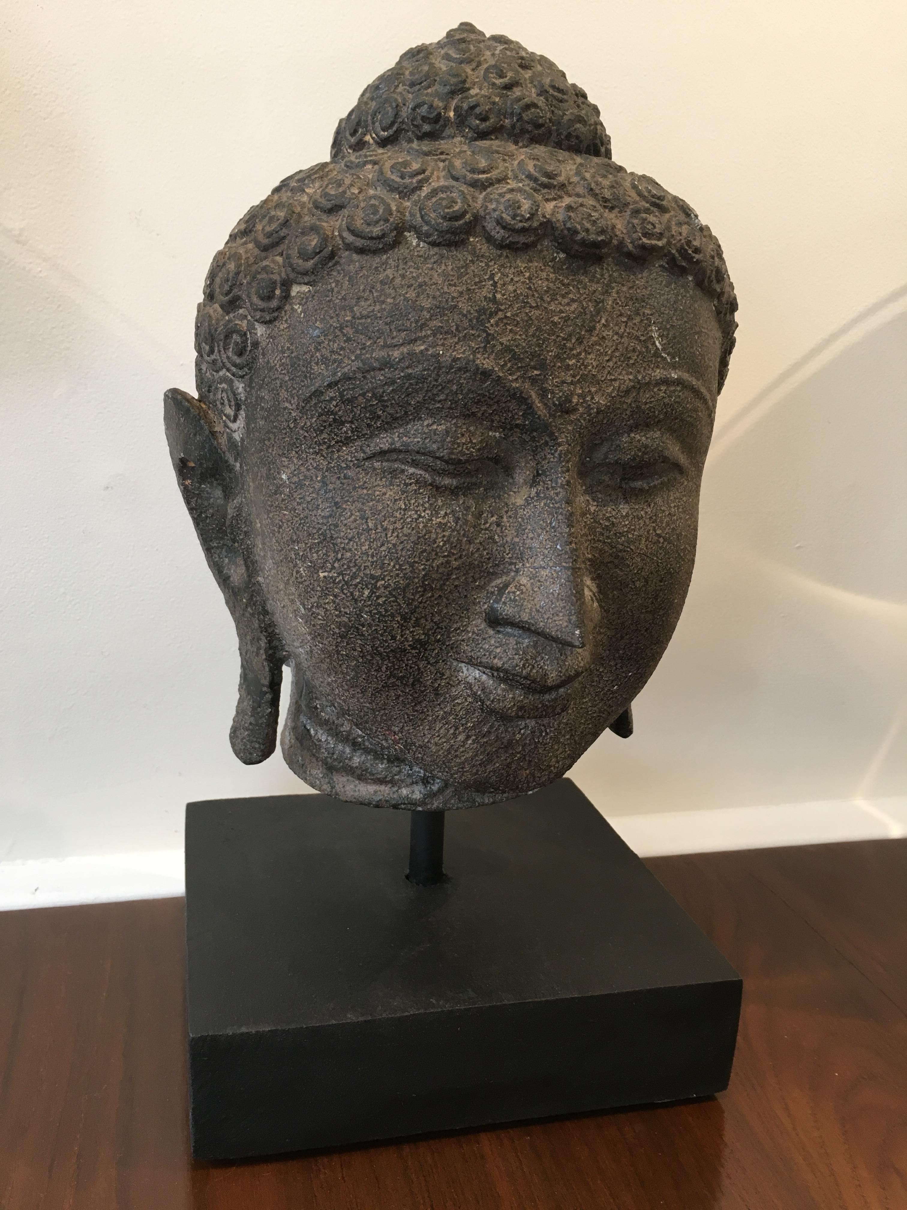 A beautiful Buddha head made of granite dating from the late 19th century. Features include the typical curled hair, elongated ears and half-closed eyes. The Ushnisha crown depicts the wisdom and illumination after attaining enlightenment. In