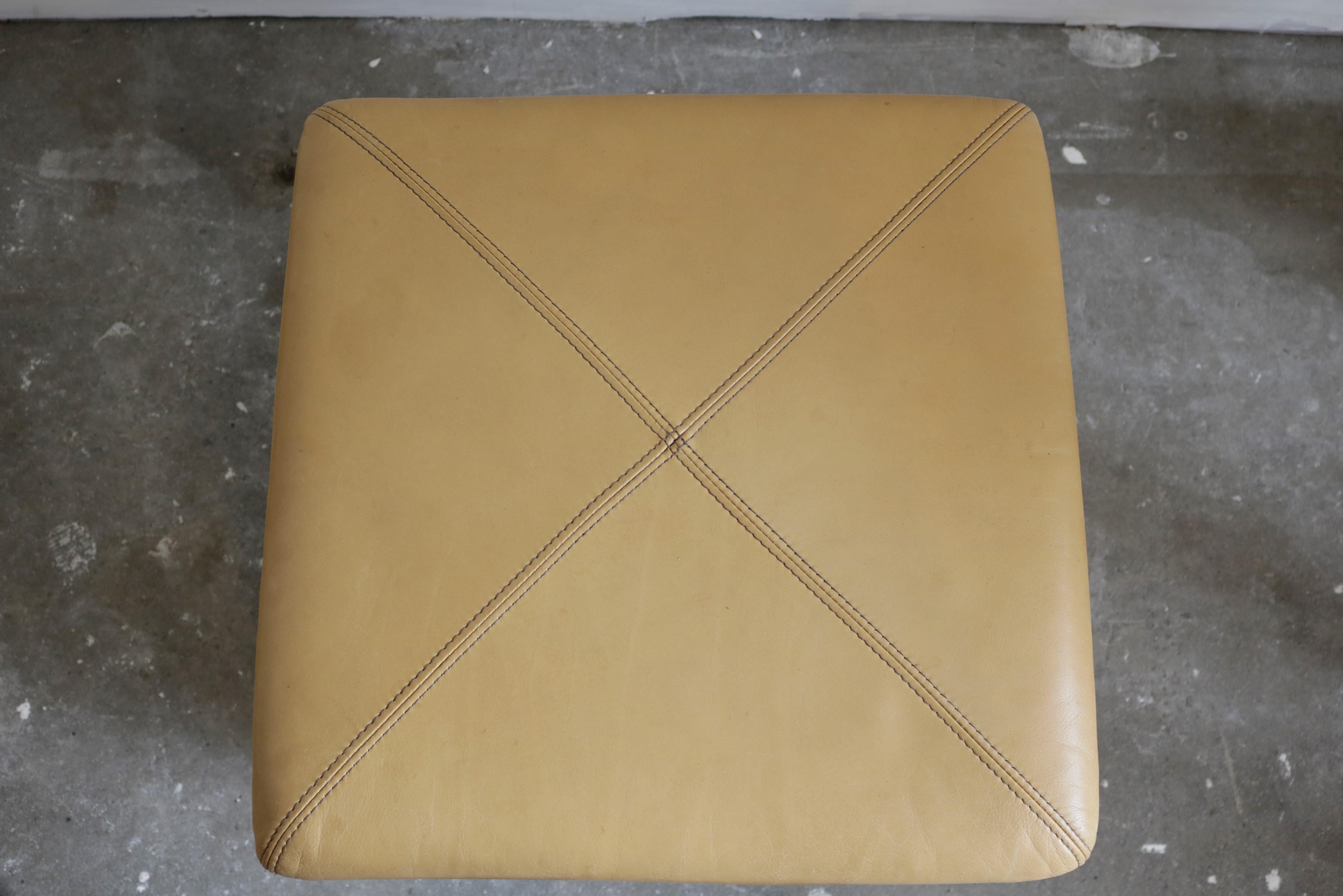 A pair of camel stitched leather stools with a walnut base.